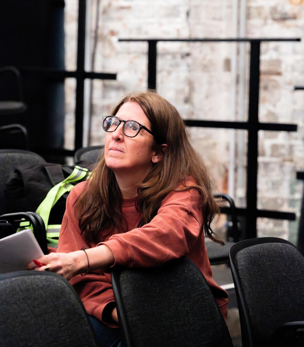 Frau sitzt auf einer bestuhlten Tribüne.