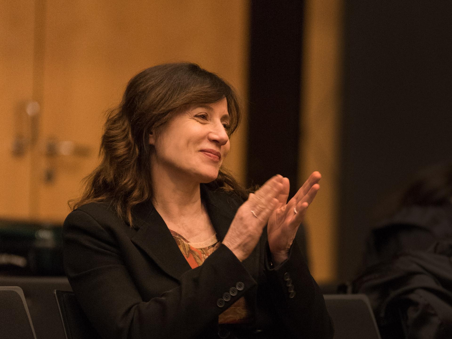 Die Komponistin Lucia Ronchetti sitzt lächelnd und klatschend im Zuschauerraum