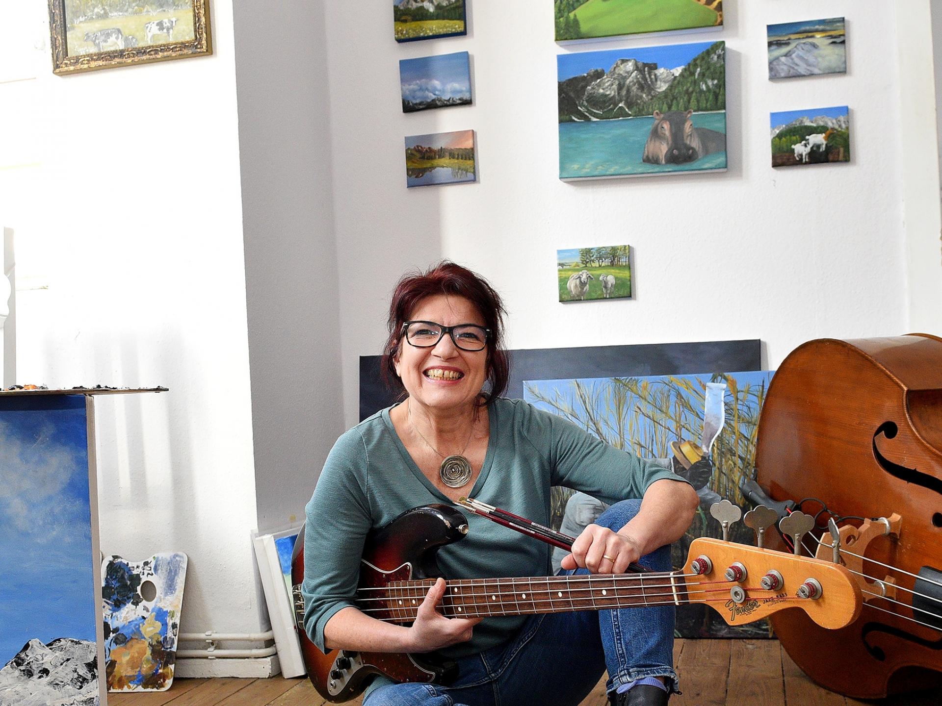Lexi Rumpel sitzt auf dem Boden mit Gitarre in der Hand