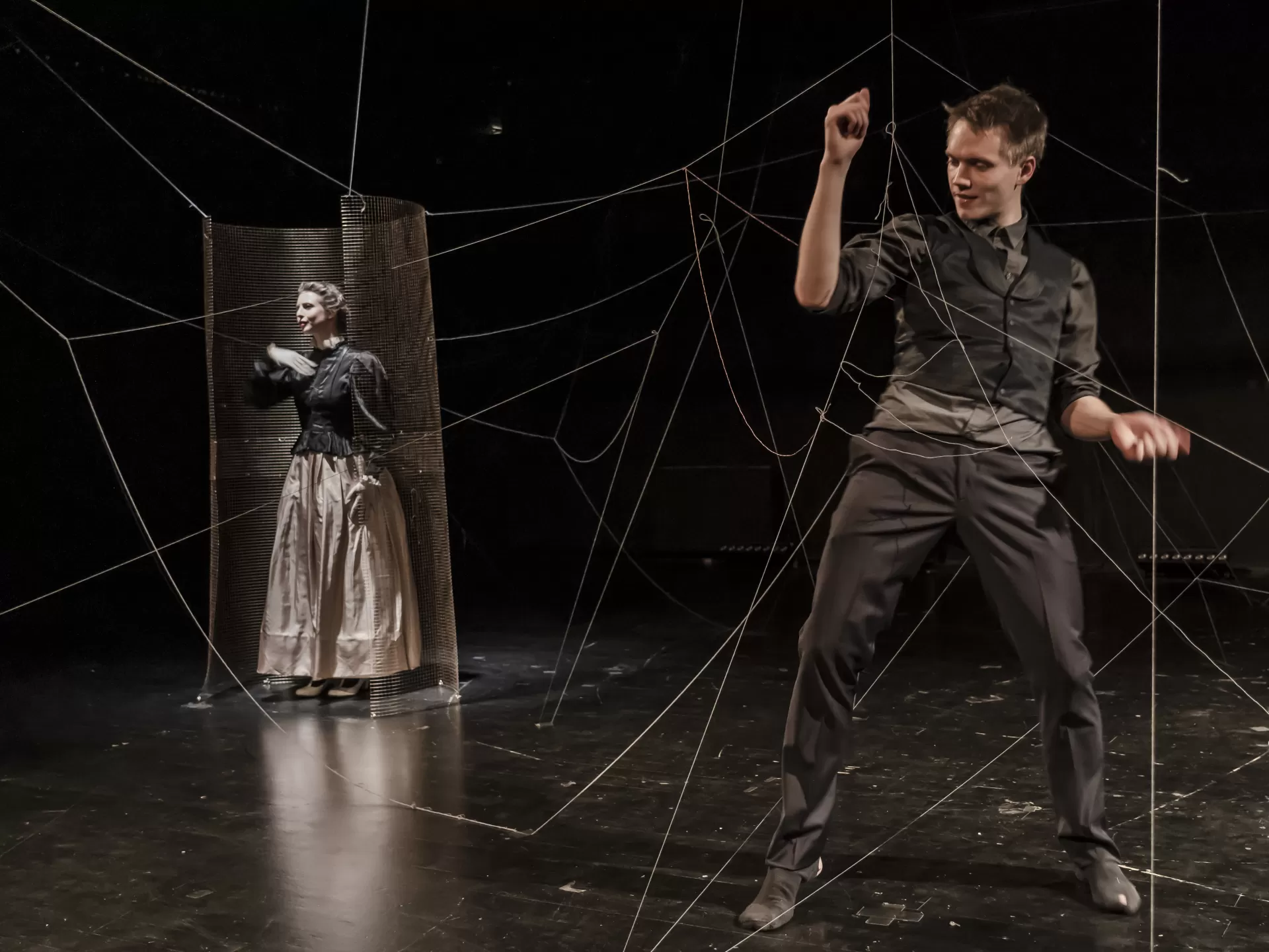 Max Böttcher in Weste und Hemd tanzt mit durch den Raum gespannten Fäden