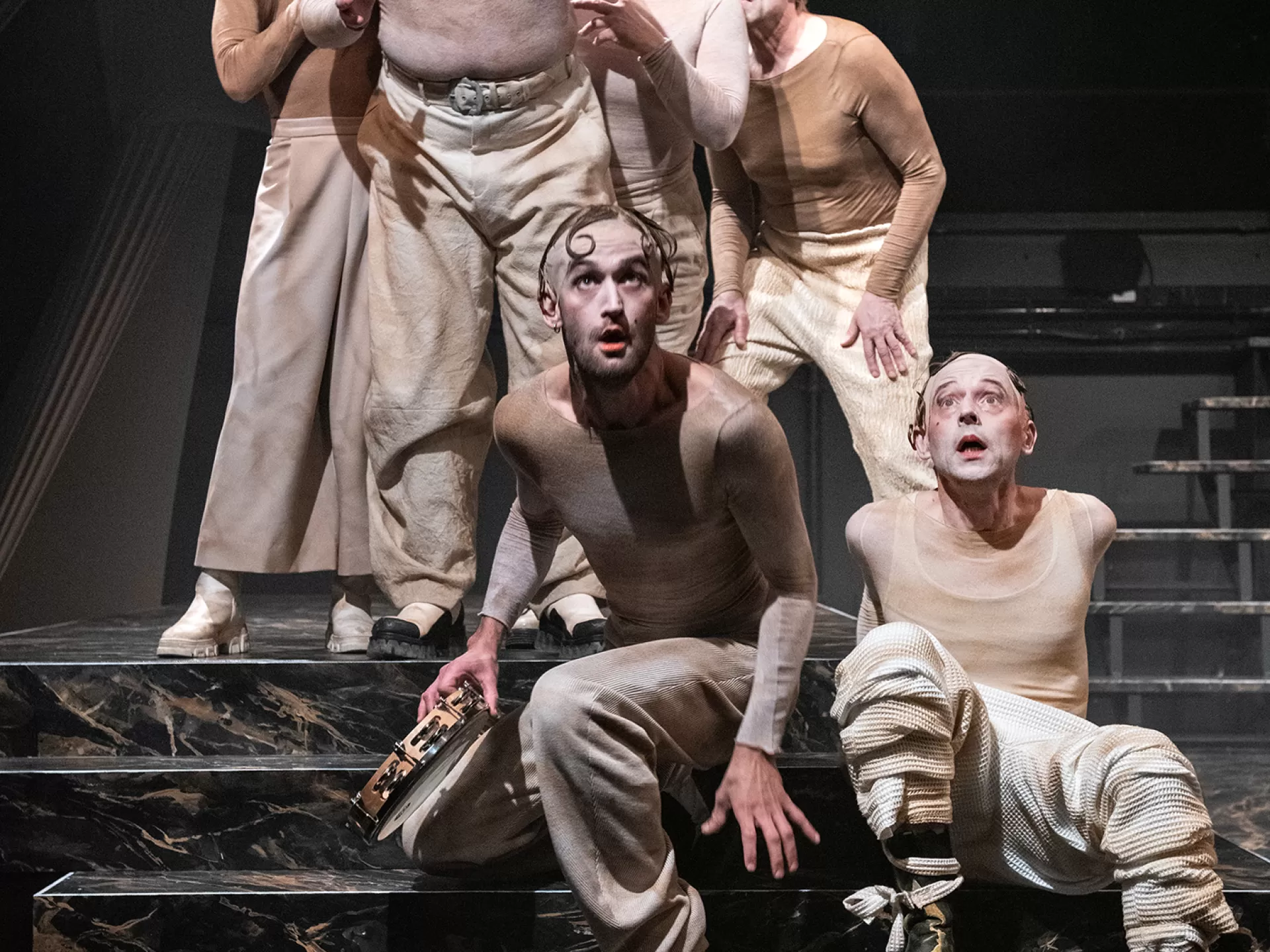 Das Ensemble sitzt auf der Bühne auf einer Treppe in der Inszenierung von "Tyll" am Theater Heidelberg im Dezember 2021.