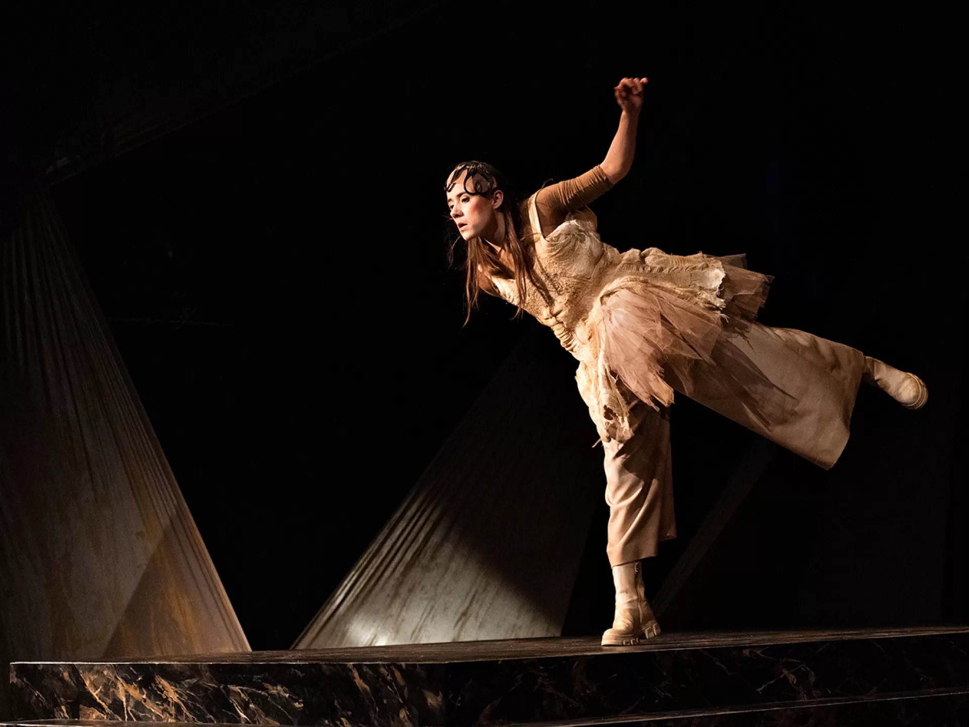 Die Figur Tyll (gespielt von Esra Schreier) steht auf einem Bein und schaut nach unten in der Inszenierung von "Tyll" am Theater Heidelberg im Dezember 2021.