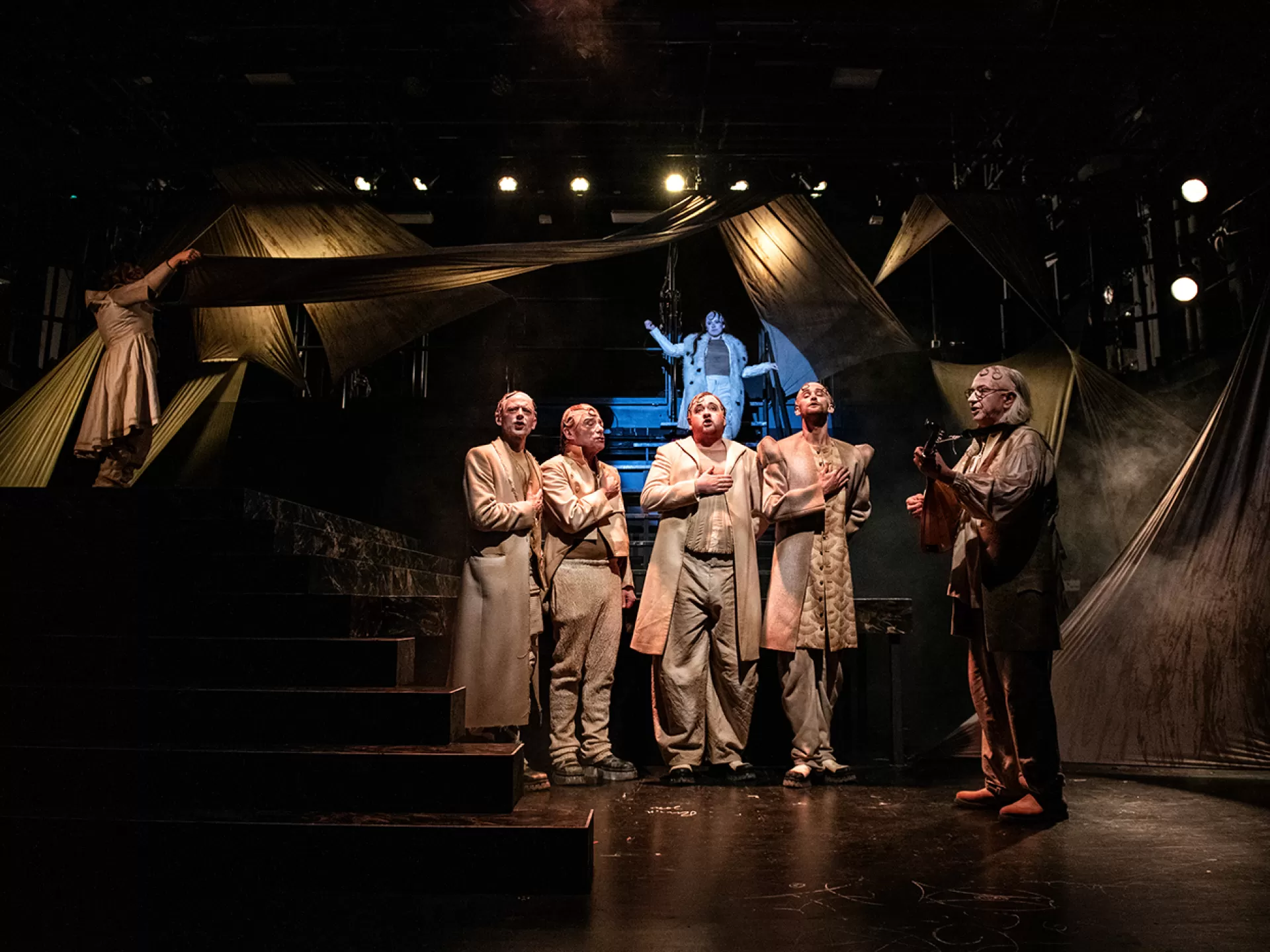 Das Ensemble steht auf der Bühne und singt, eine Figur spielt Gitarre in der Inszenierung von "Tyll" am Theater Heidelberg im Dezember 2021.