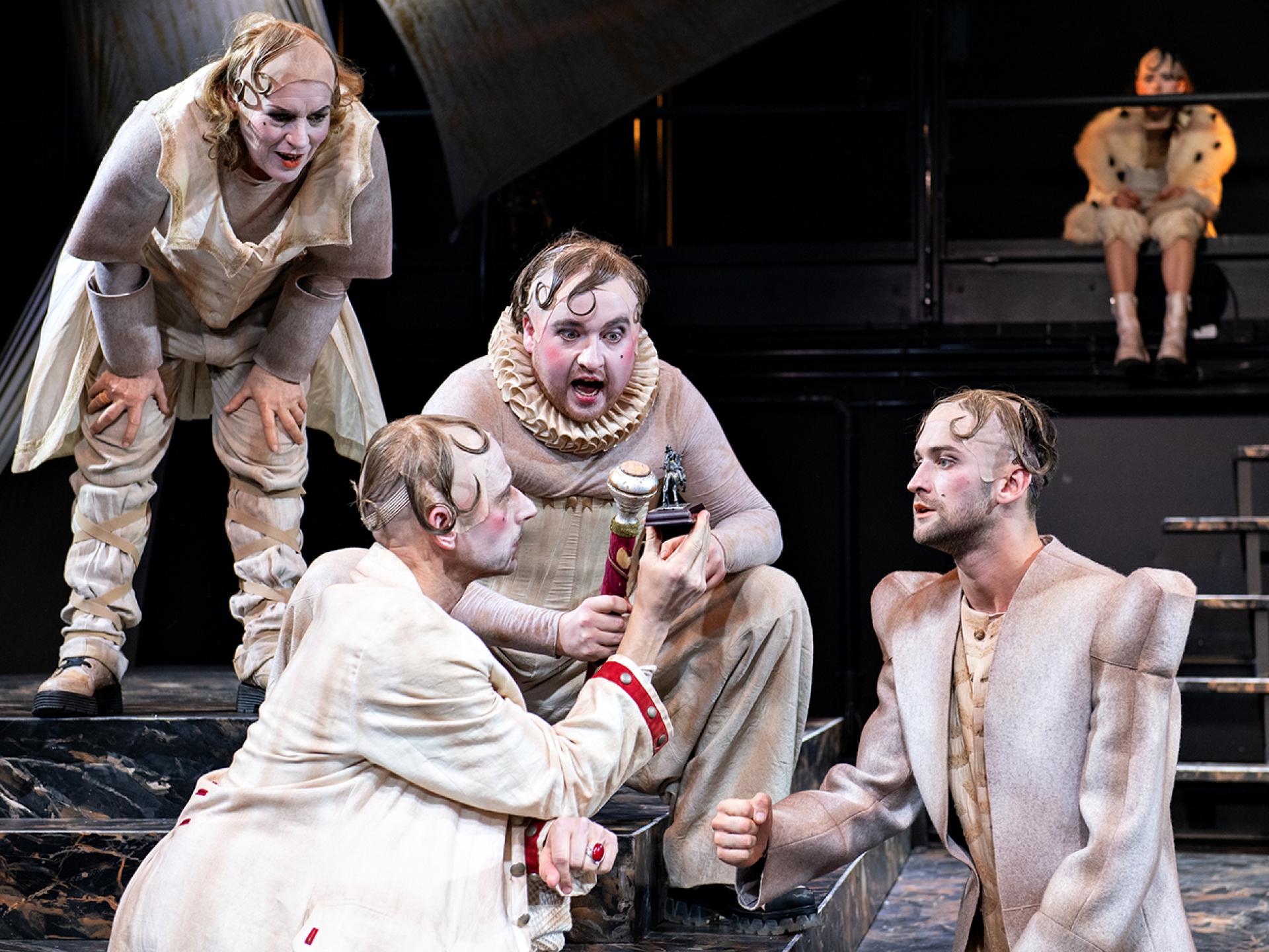Tyll (gespielt von Elisabeth Auer) schaut die drei Figuren Kürassier, Gustav Adolf und Friedrich an, im Hintergrund sitzt Elizabeth in der Inszenierung von "Tyll" am Theater Heidelberg im Dezember 2021.