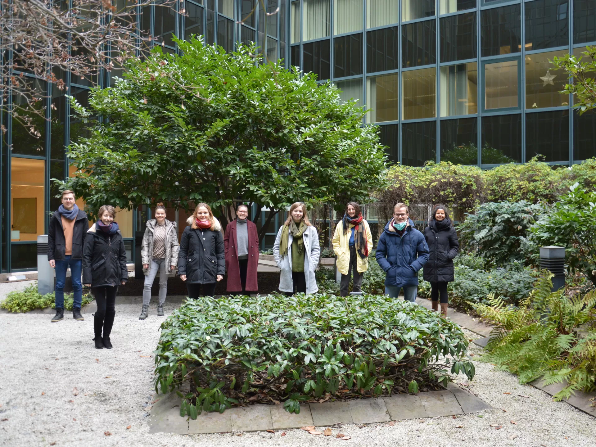 Gruppenfoto der neun Studierenden aus dem Jahrgang 22, in zwei Reihen vor einem Baum im Innhof stehend