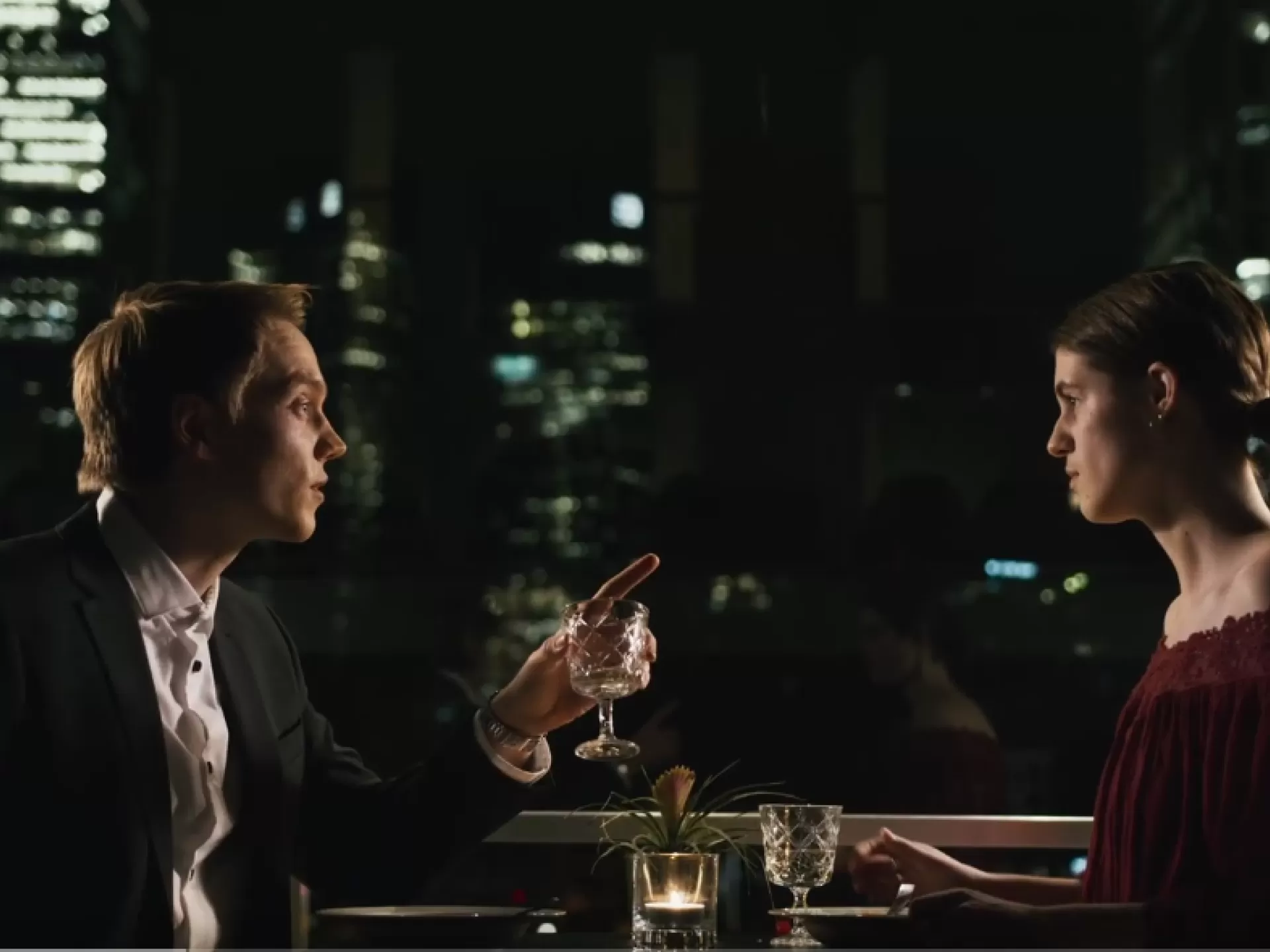 Ein Mann und eine Frau sitzen in einem Restaurante vor der Skyline Frankfurts.