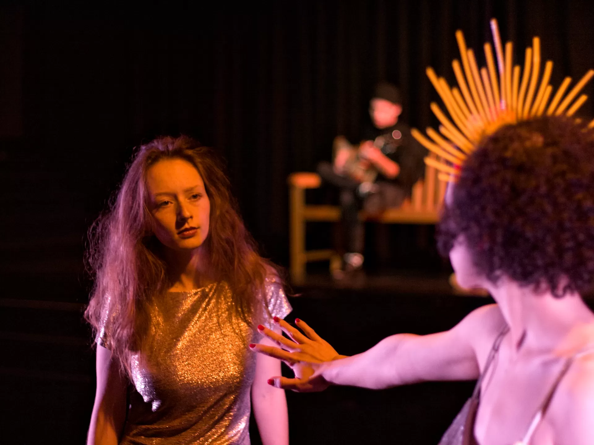 Eine Frau steht vor einer zweiten und hebt abwehrend die Hand.