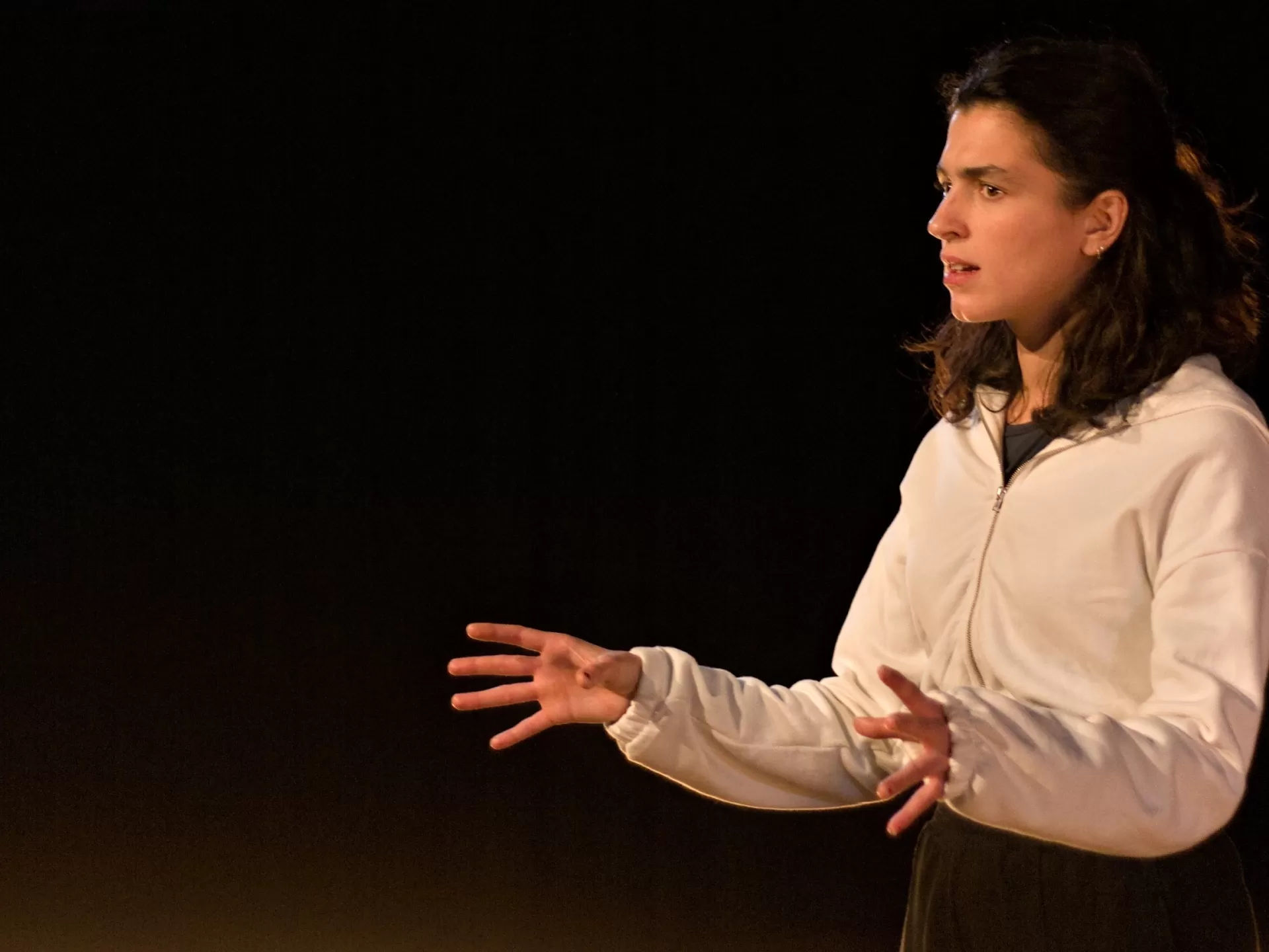 Eine Frau steht mit beiden Händen vor dem Körper und spricht ernst.