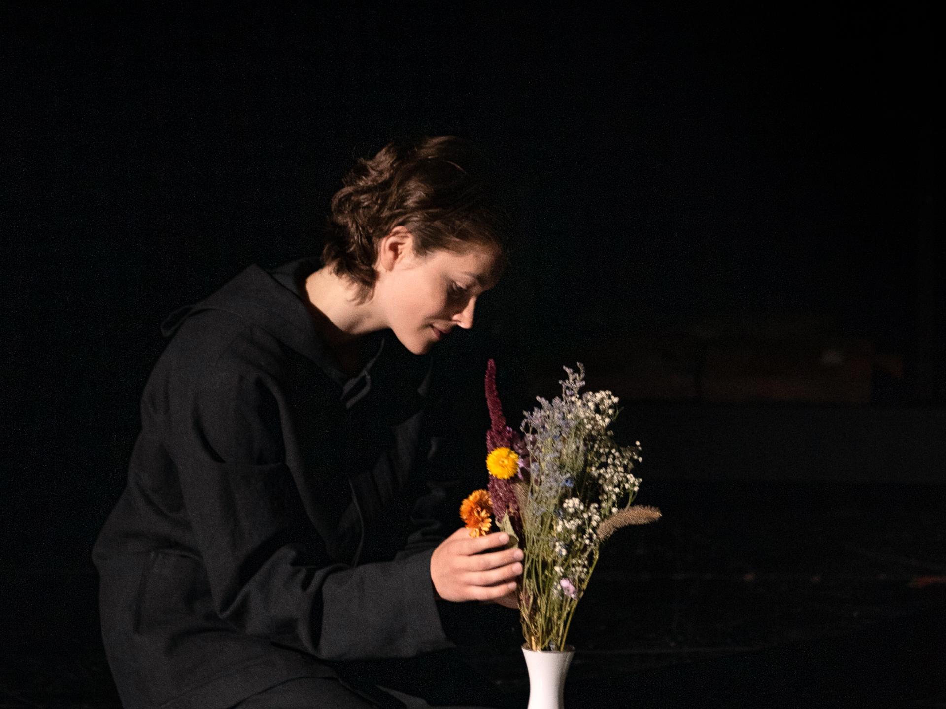 Schauspielerin, die bunte Feldblumen in einer Vase arrangiert.