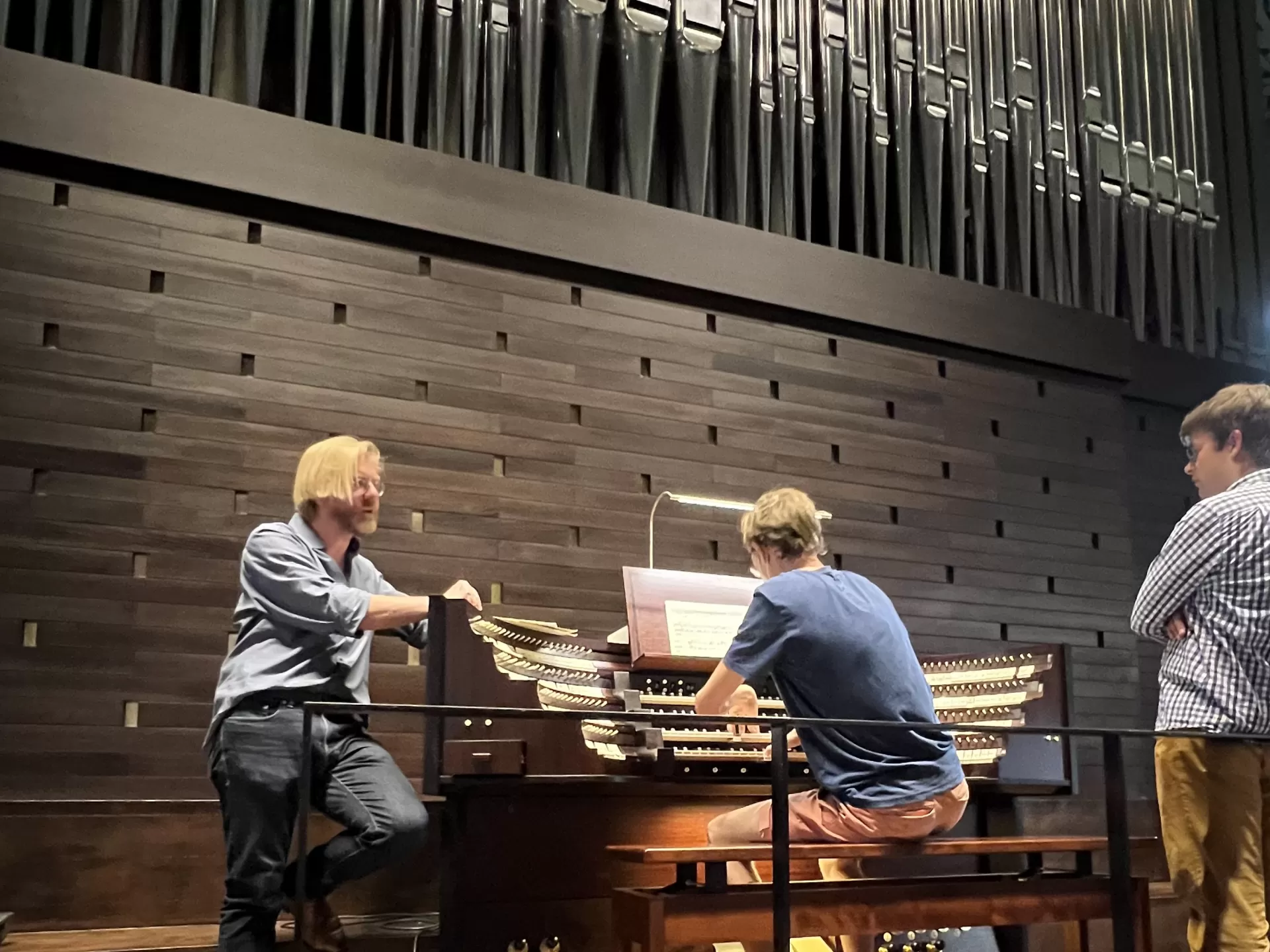 ein Schnappschuss der Unterrichtssituation: Carsten Wiebusch unterrichtet, ein Student spielt Orgel und ein weiterer hört zu.