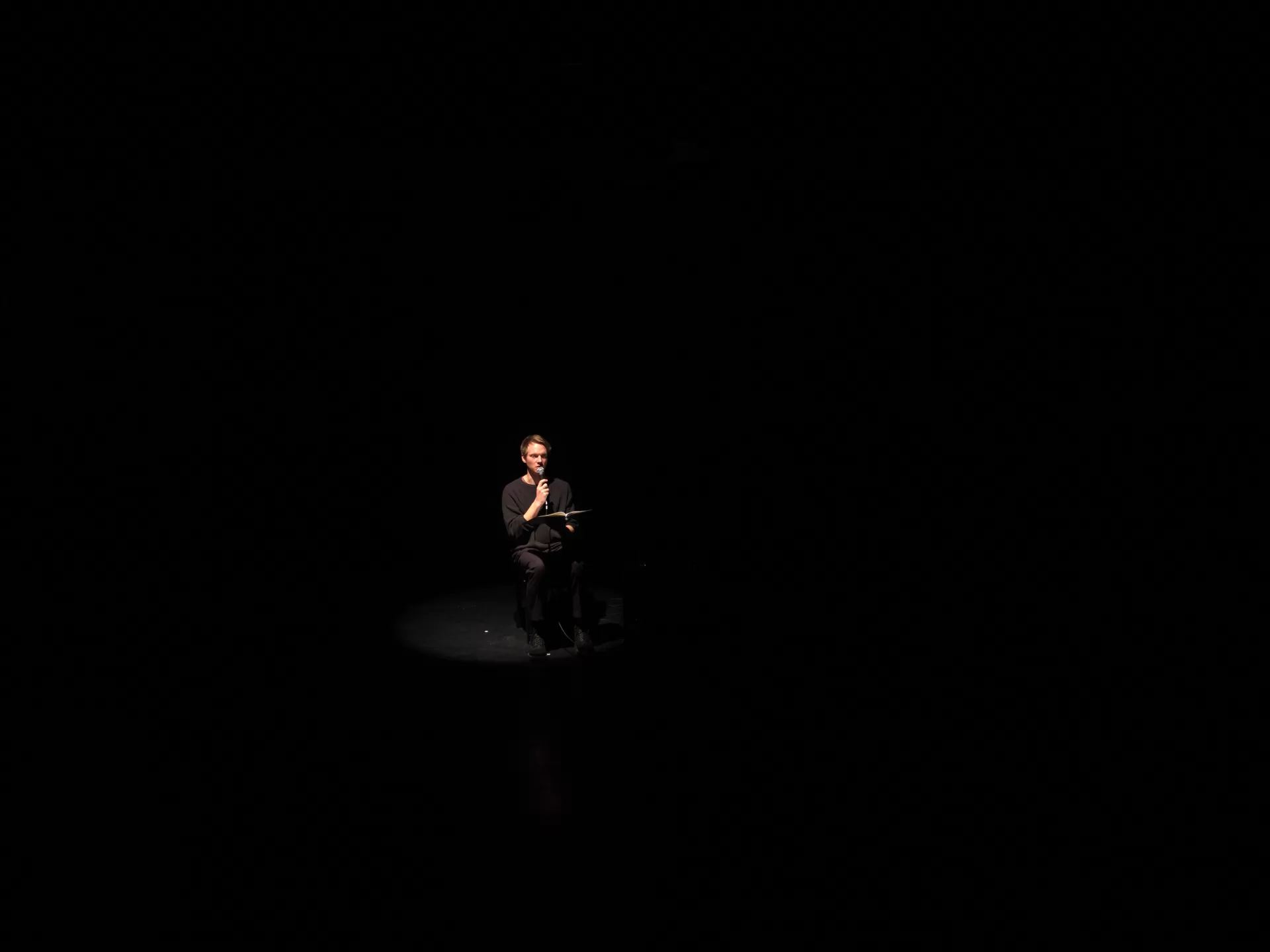 Ein Schauspieler sitzt in einem ansonsten dunklen Raum