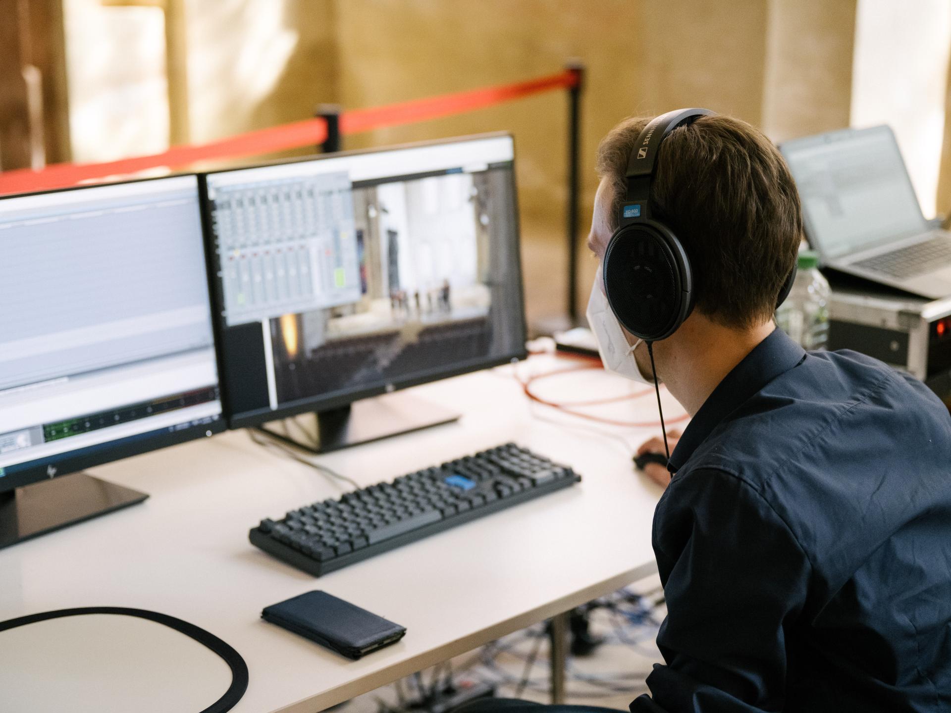 Eine Person sitzt am Computer, der im Kloster Eberbach aufgebaut ist und auf dem die Regie der Videoproduktion zu sehen ist.