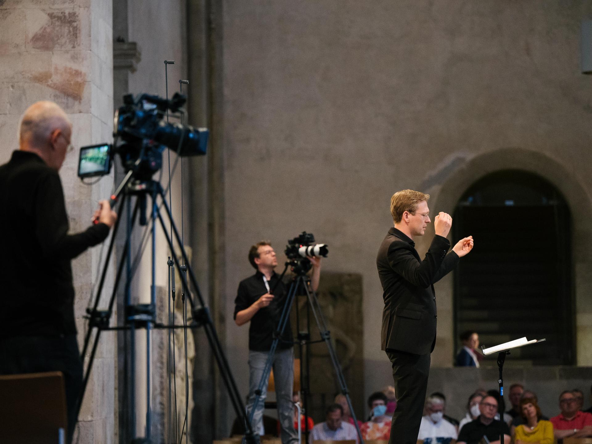 Zwei Kameraleute und ein Dirigent auf der Bühne im Kloster Eberbach