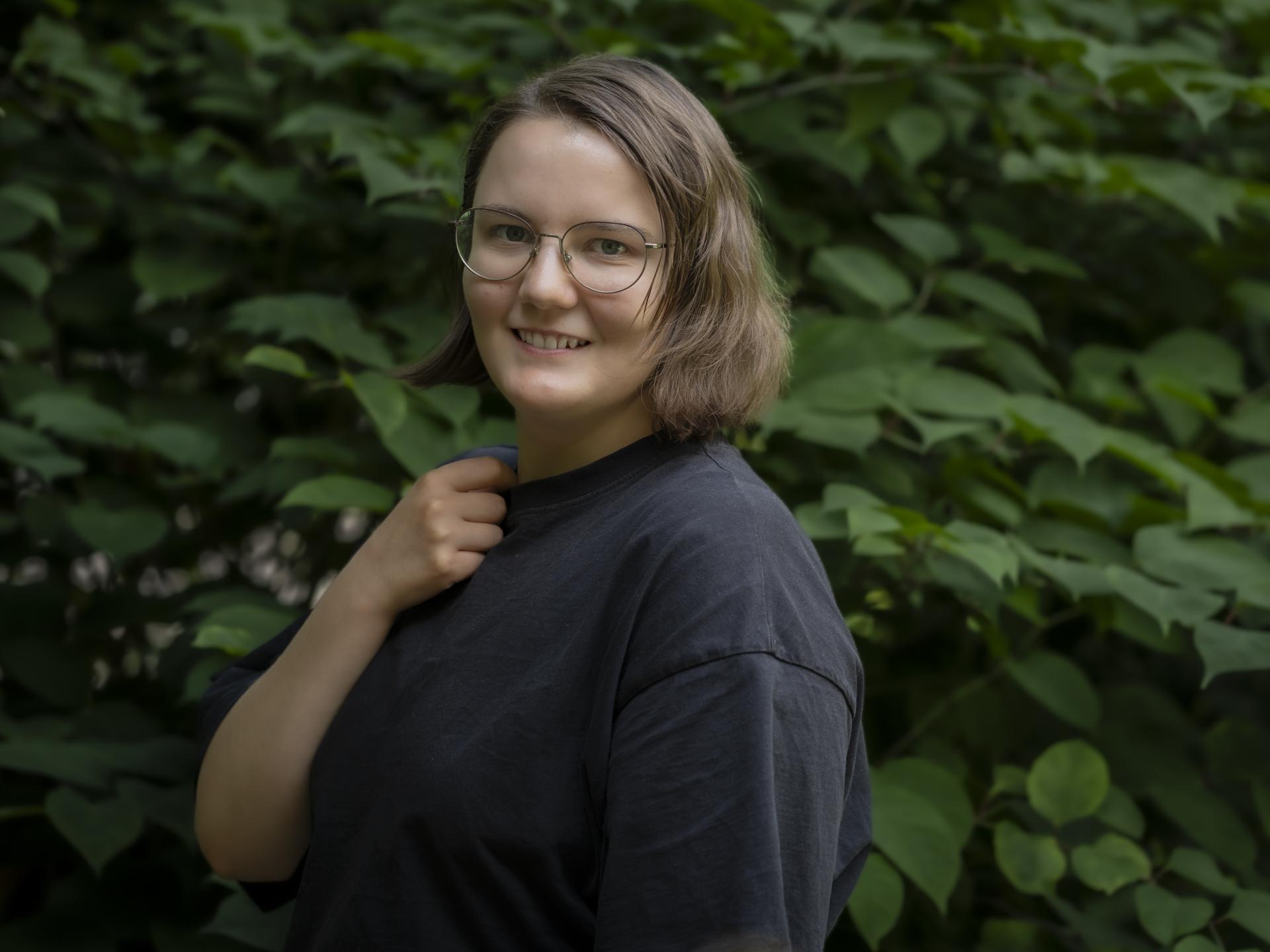 Ein Portrait der Studierenden Elena Pogorelova vor einem Gebüsch