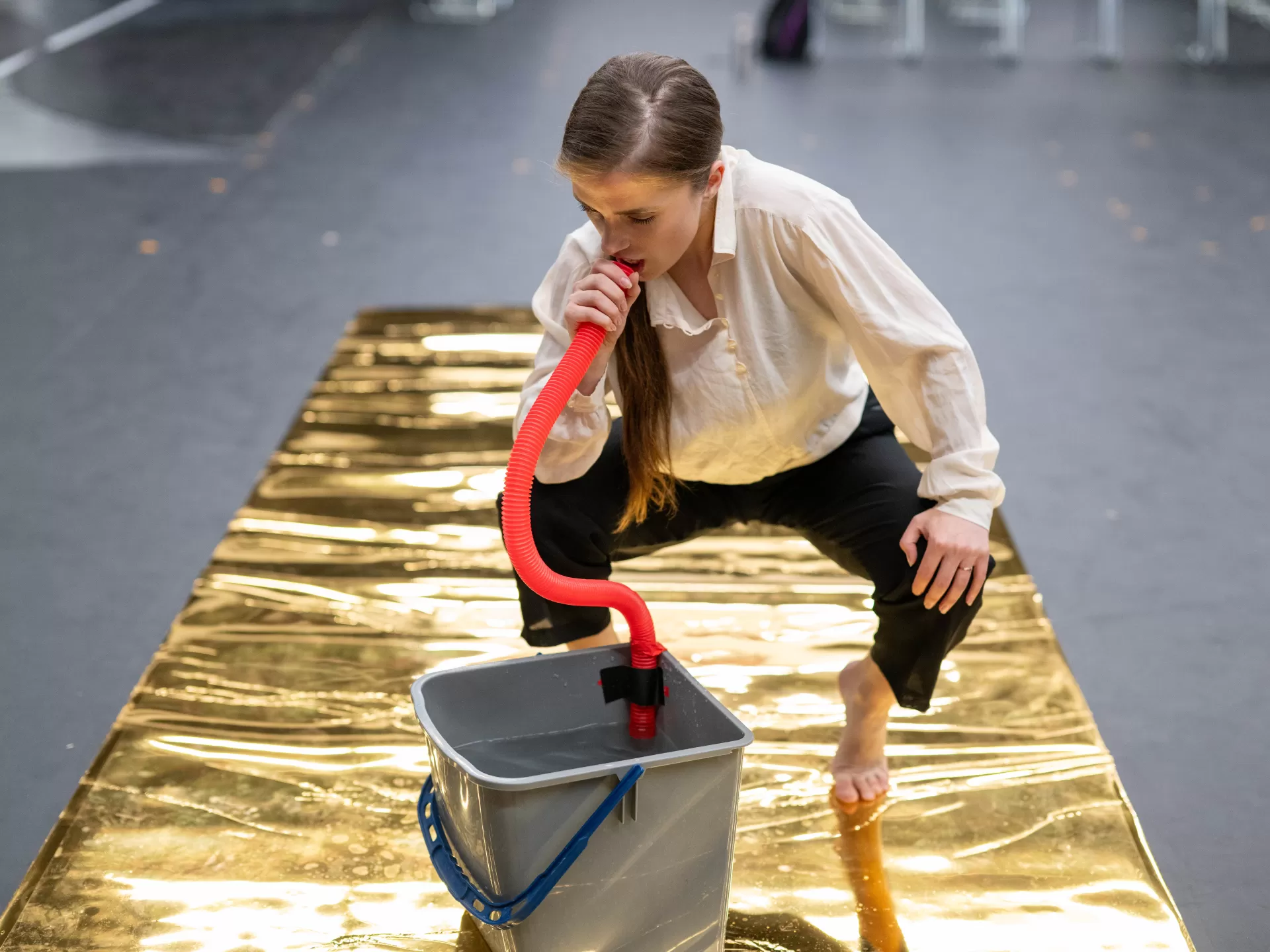 Probe eines Musiktheaterstücks: Sängerin hält sich ein rotes Rohr an den Mund