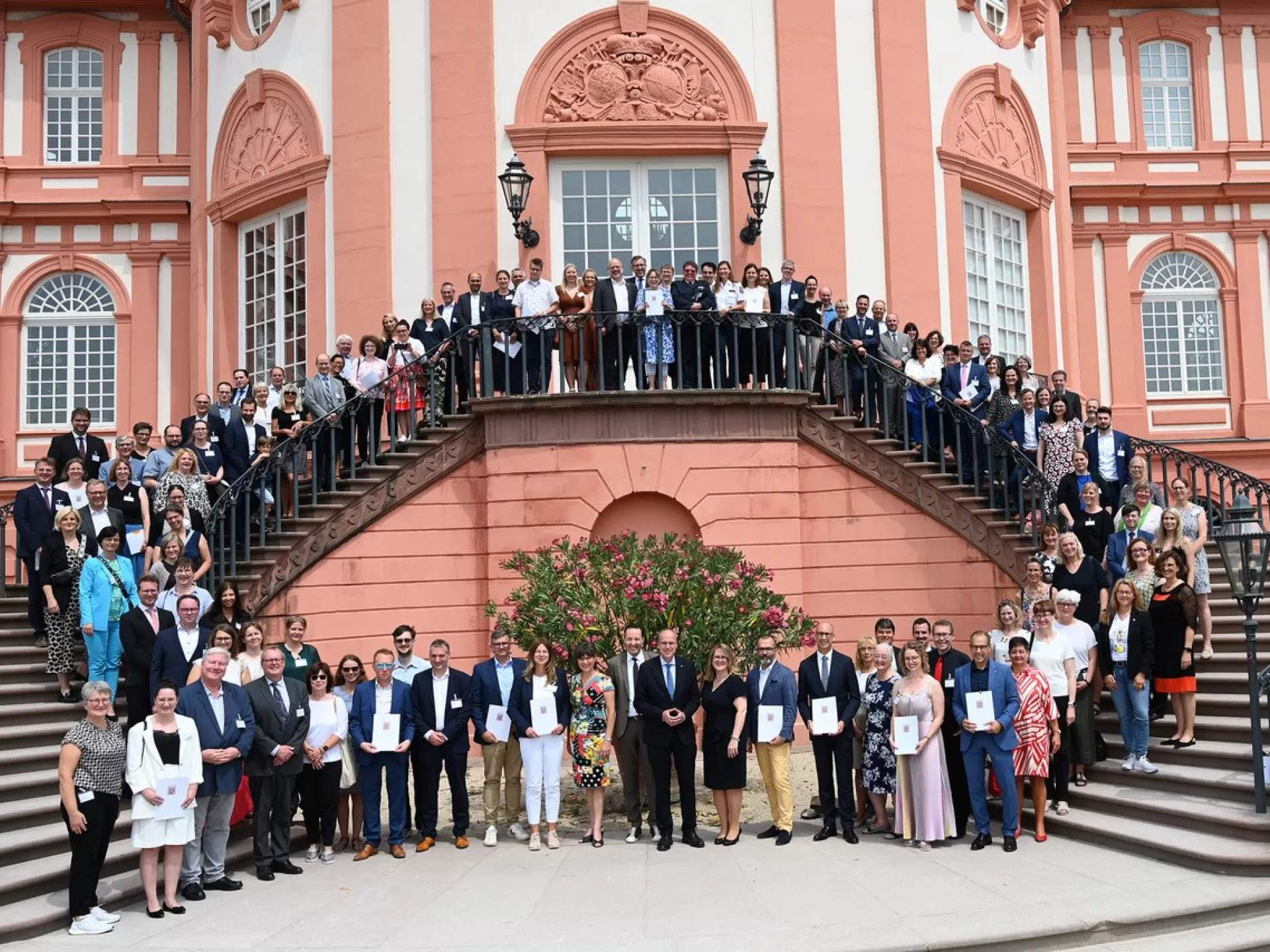 Eine große Gruppe Vertreter*innen der hessischen Dienststellen auf den Schloss-Treppenstufen in Wiesbaden bei der Verleihung des Gütesiegels "Familienfreundlicher Arbeitgeber".