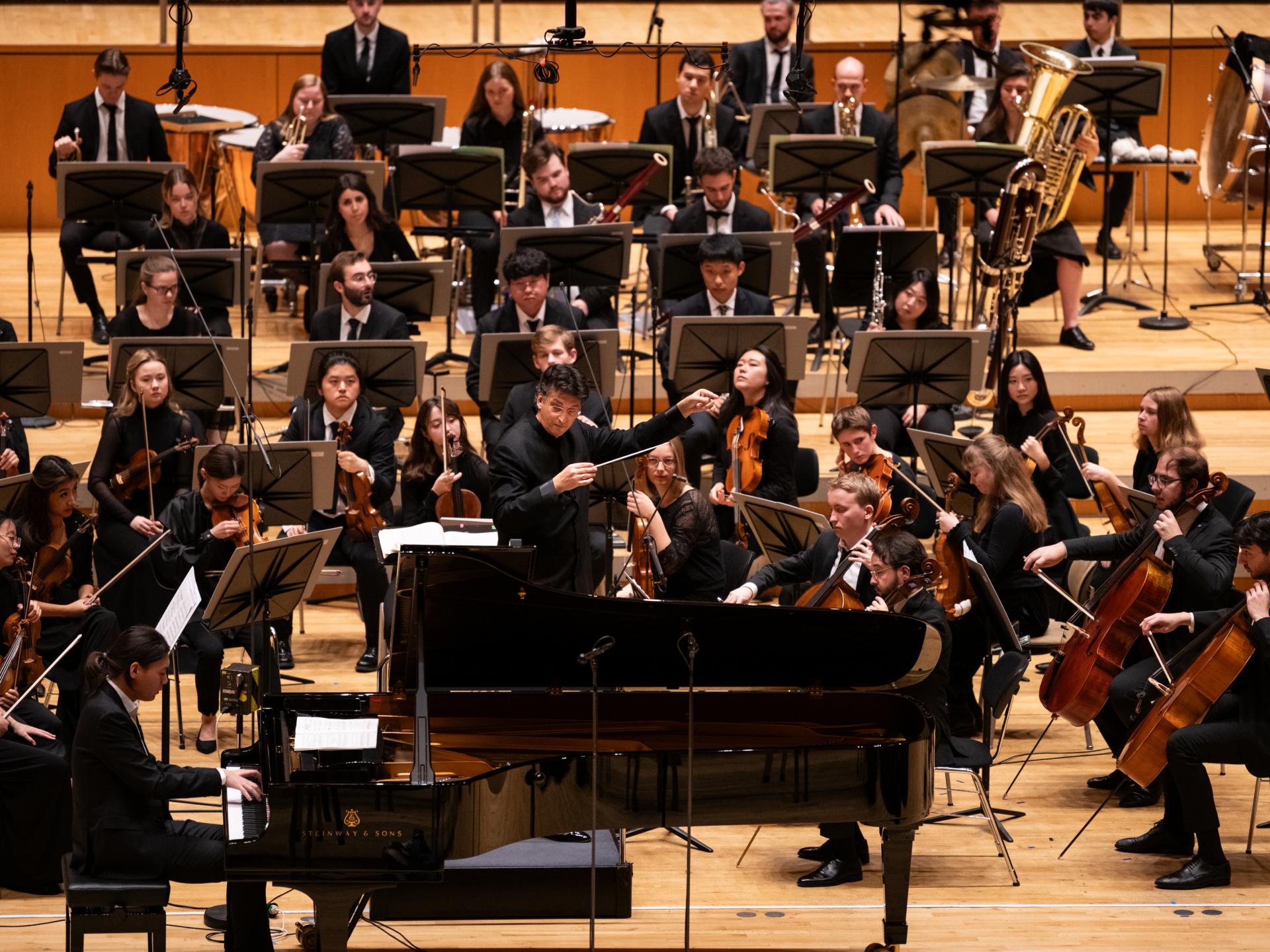 Zu sehen ist das HfMDK Symphonieorchester mit einem Solisten am Flügel.
