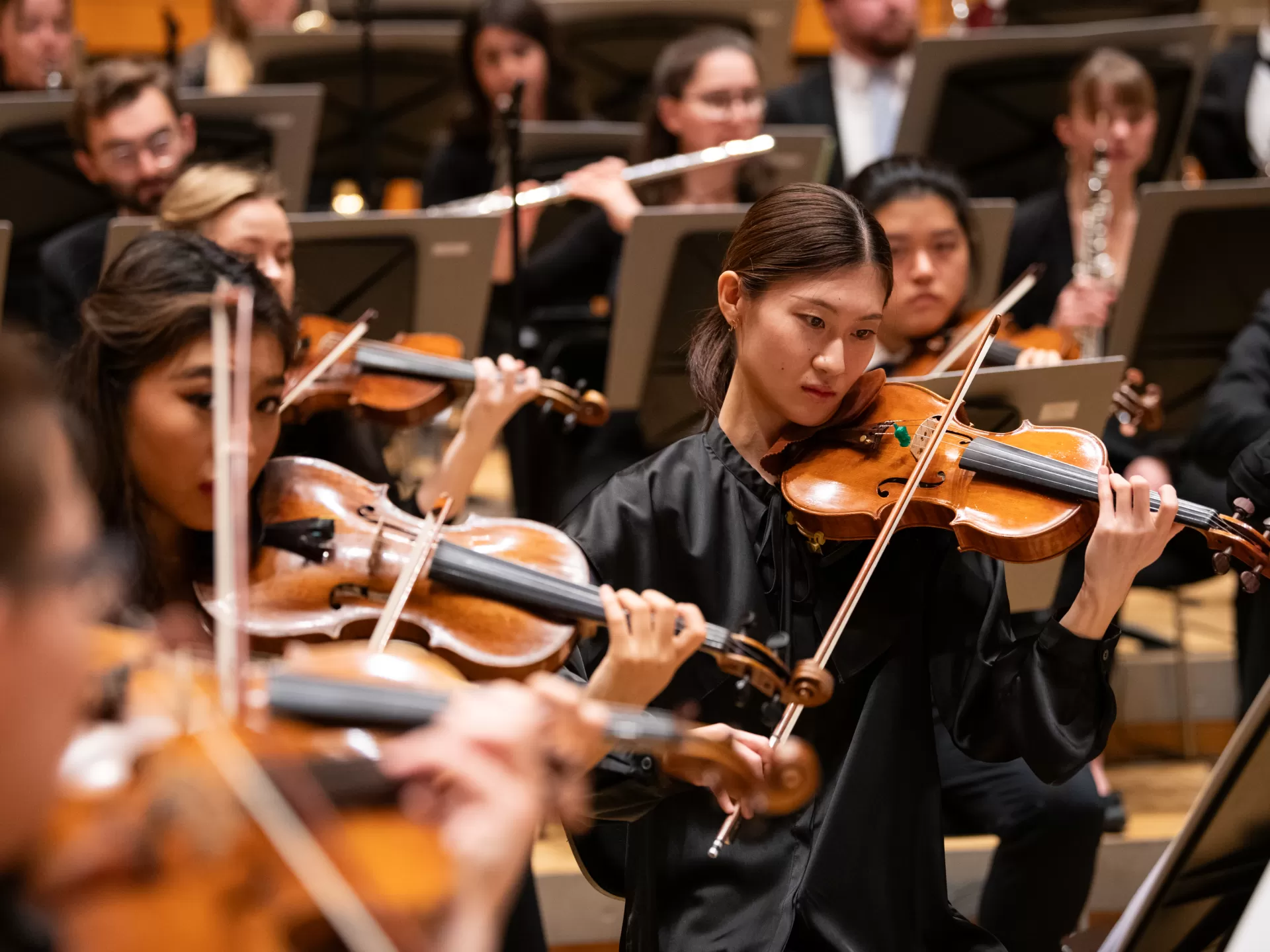 Eine Studentin inmitten des Orchesters spielt Geige