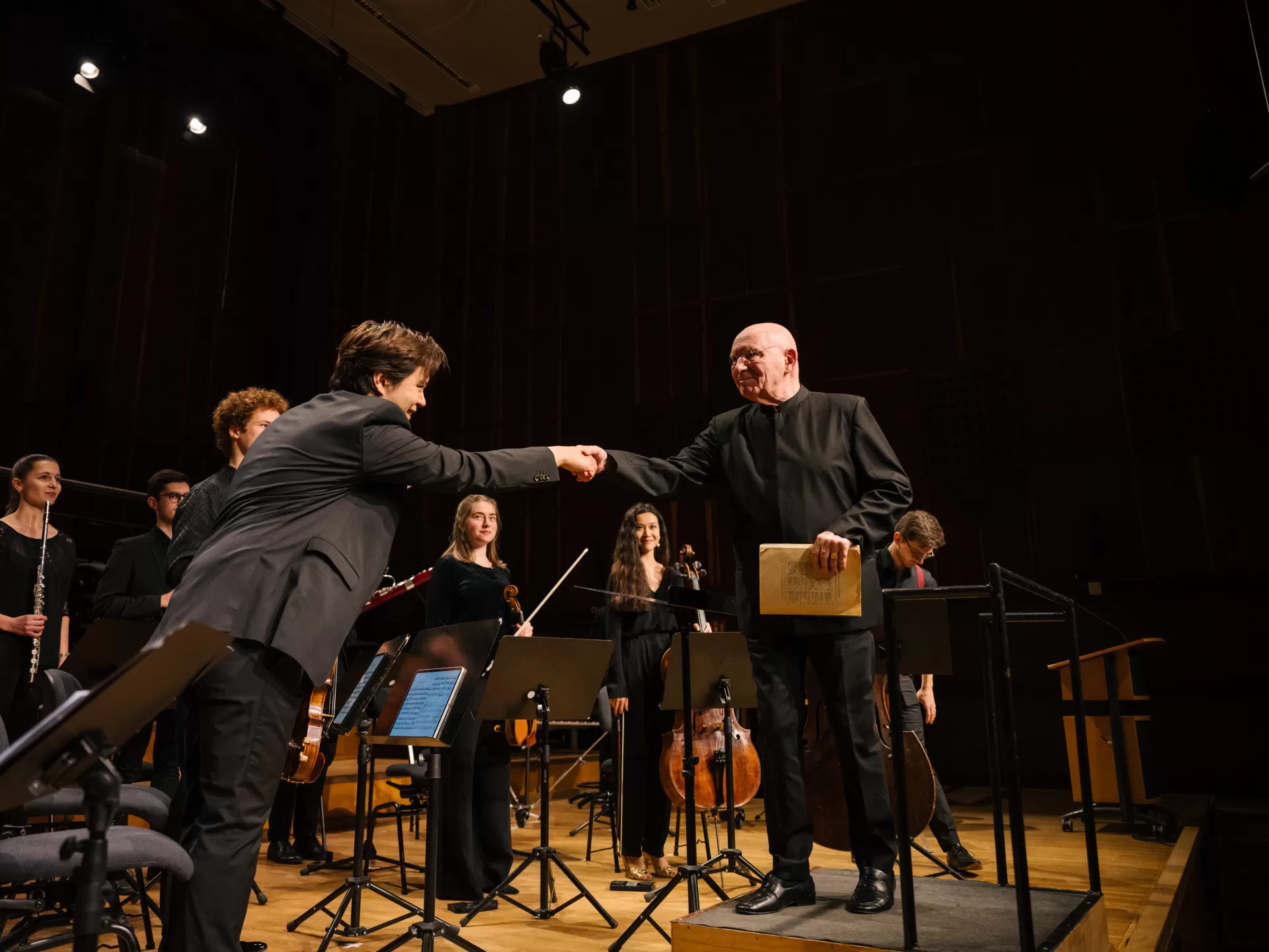 Christoph Eschenbach gibt dem ersten Geiger des Studierendenensembles die Hand