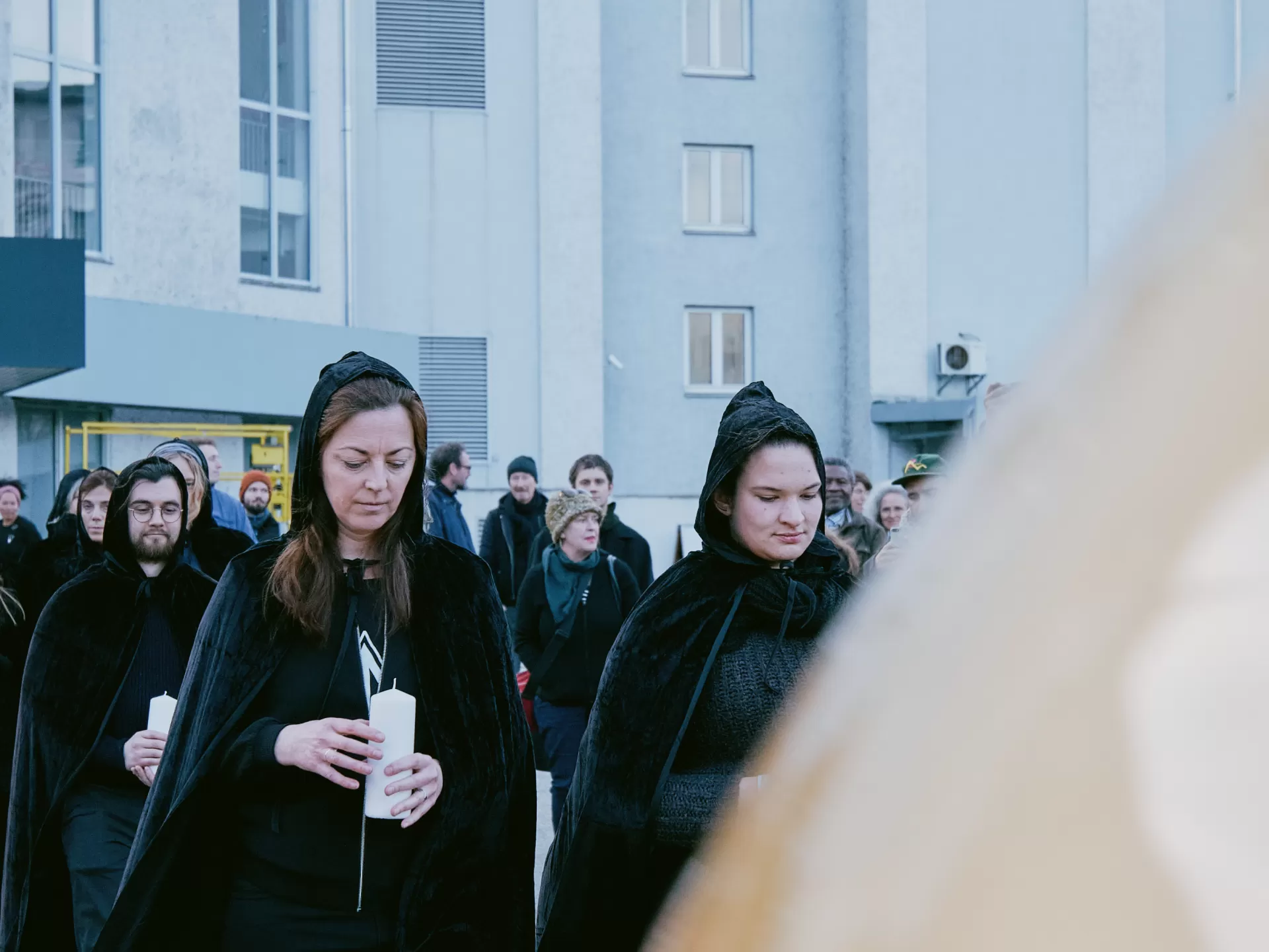 Die Personen in schwarzen Kutten stehen hinter der goldenen Kugel und blicken hinunter auf ihre Kerzen.