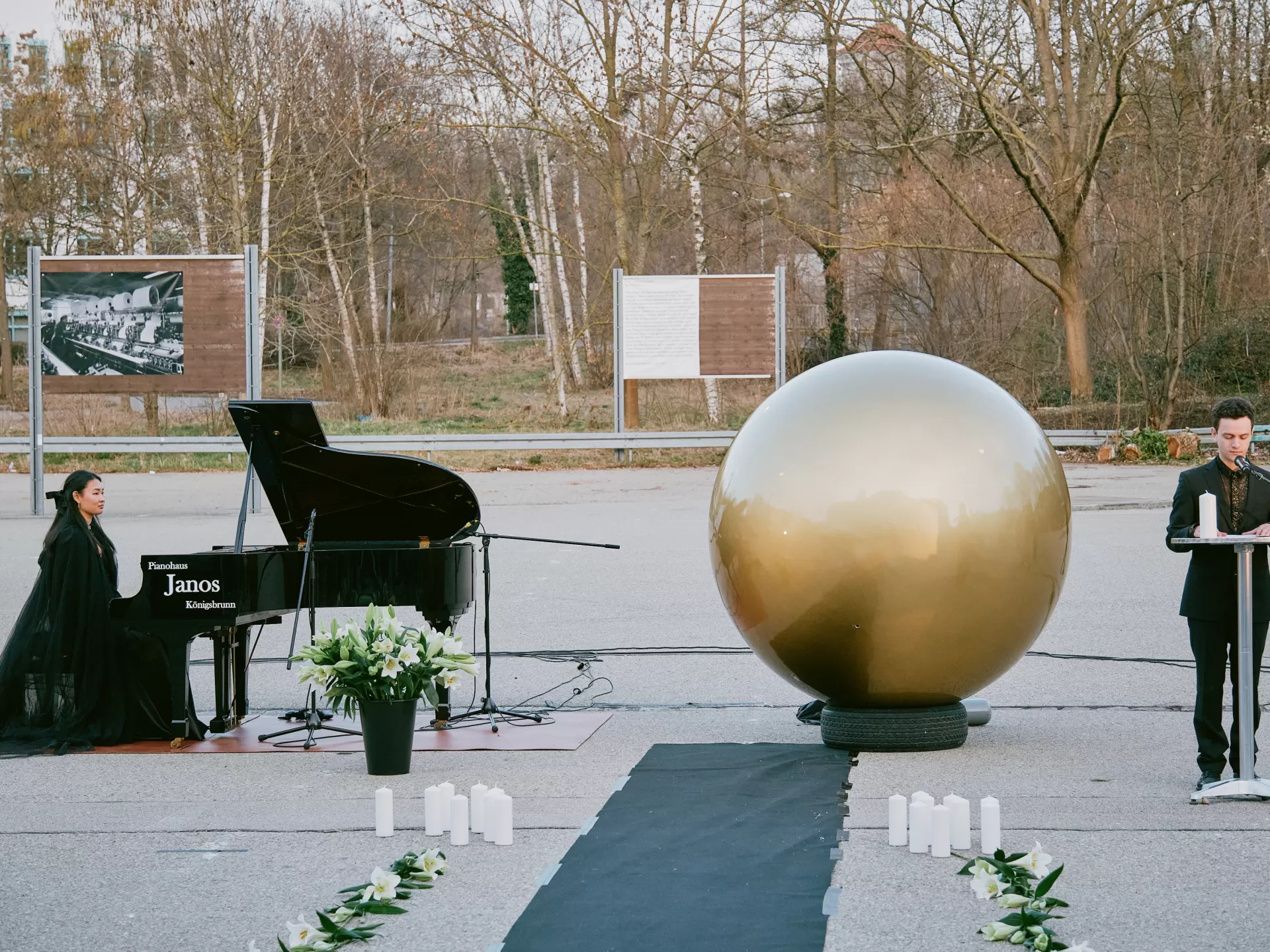 Links die Pianistin, in der Mitte die goldene Kugel, rechts ein Trauerredner an einem Pult.
