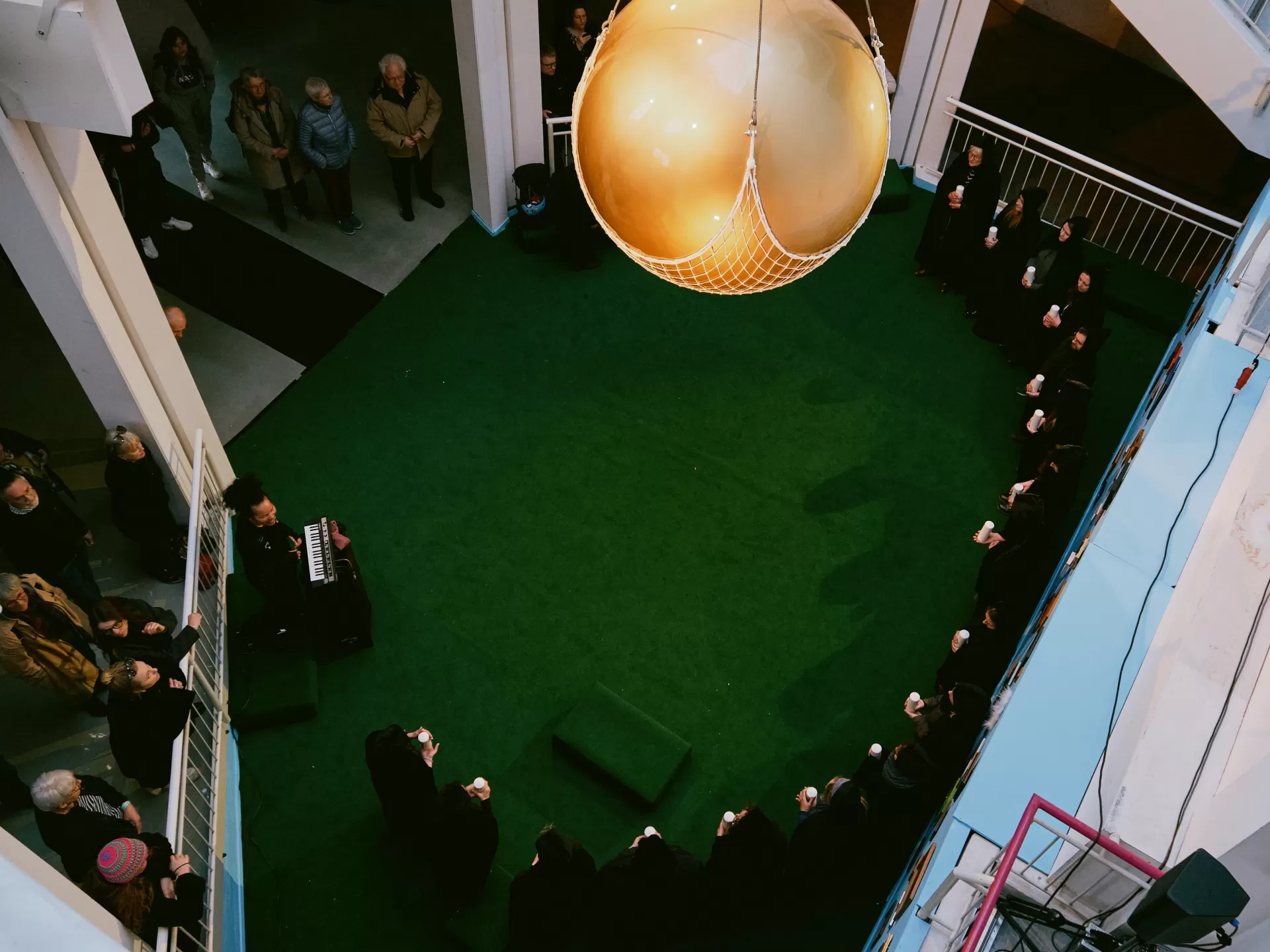 Die Goldene Kugel hängt über den in schwarzen Kutten gekleideten Mitwirkenden.