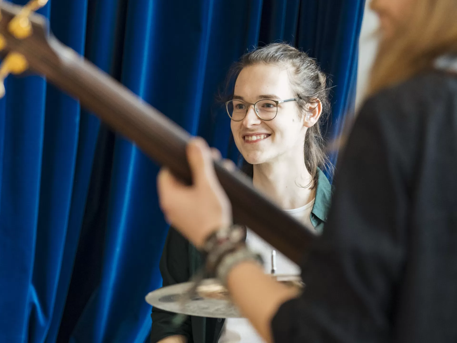 Ein lächelnder Schlagzeuger im Band-Coaching. Vorne rechts ist unscharf der Bassist zu sehen.