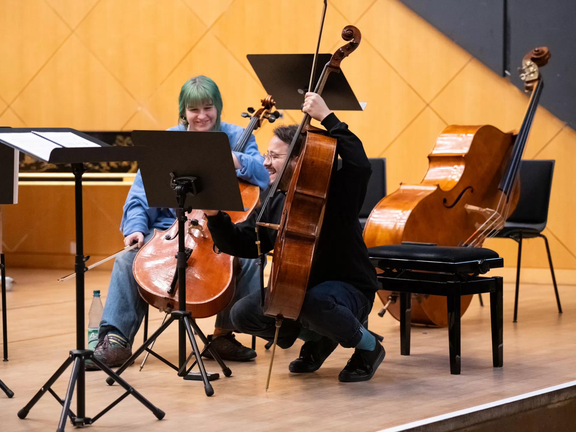 Eine Cellistin und ein Cellist lachen gemeinsam während einer Probe im Kleinen Saal