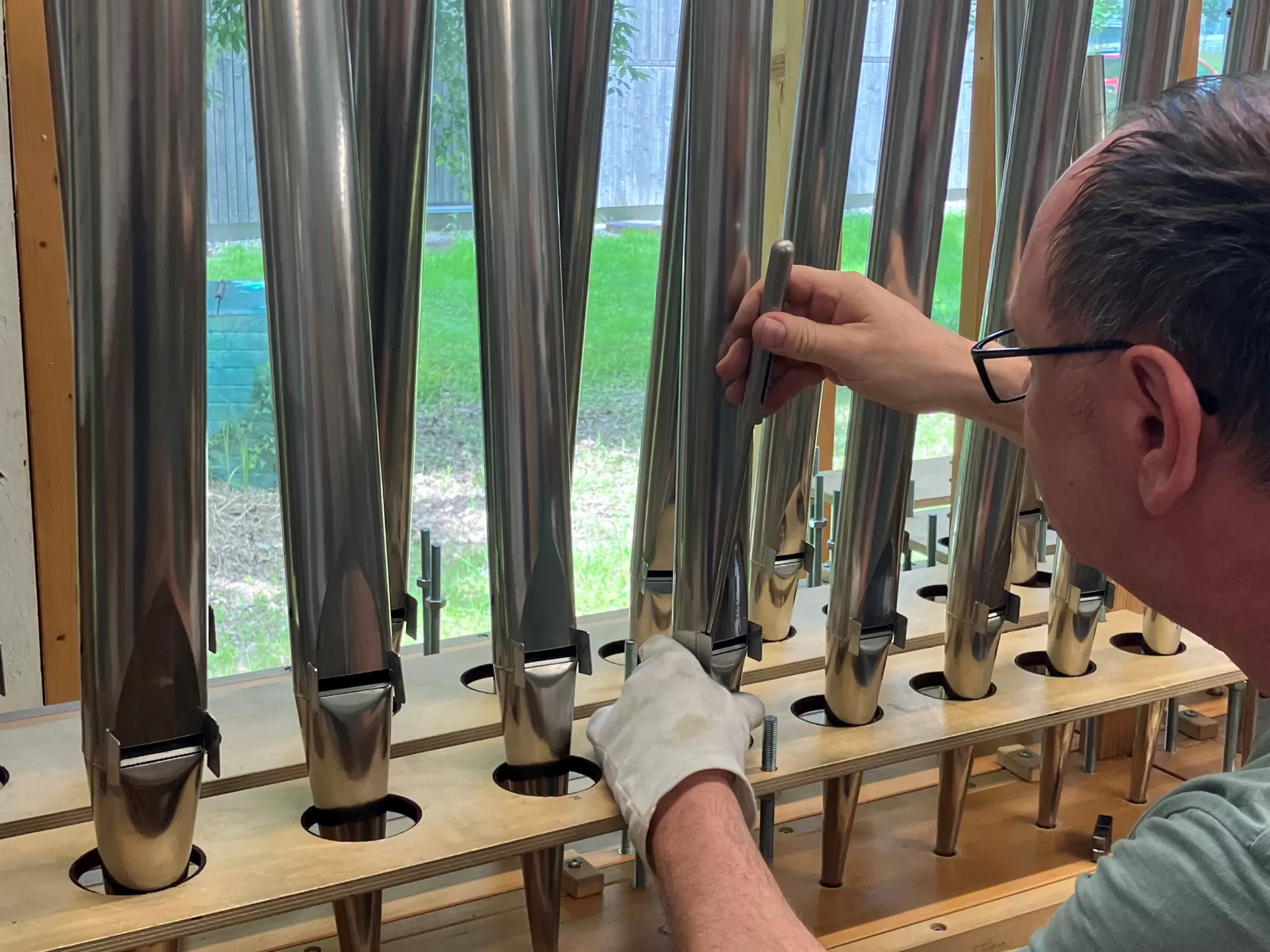 Ein Mitarbeiter bei der Vorintonation der Pfeifen. Er trägt einen Handschuh an der linken Hand und steckt einen Stab in den Aufschnitt einer Pfeife.