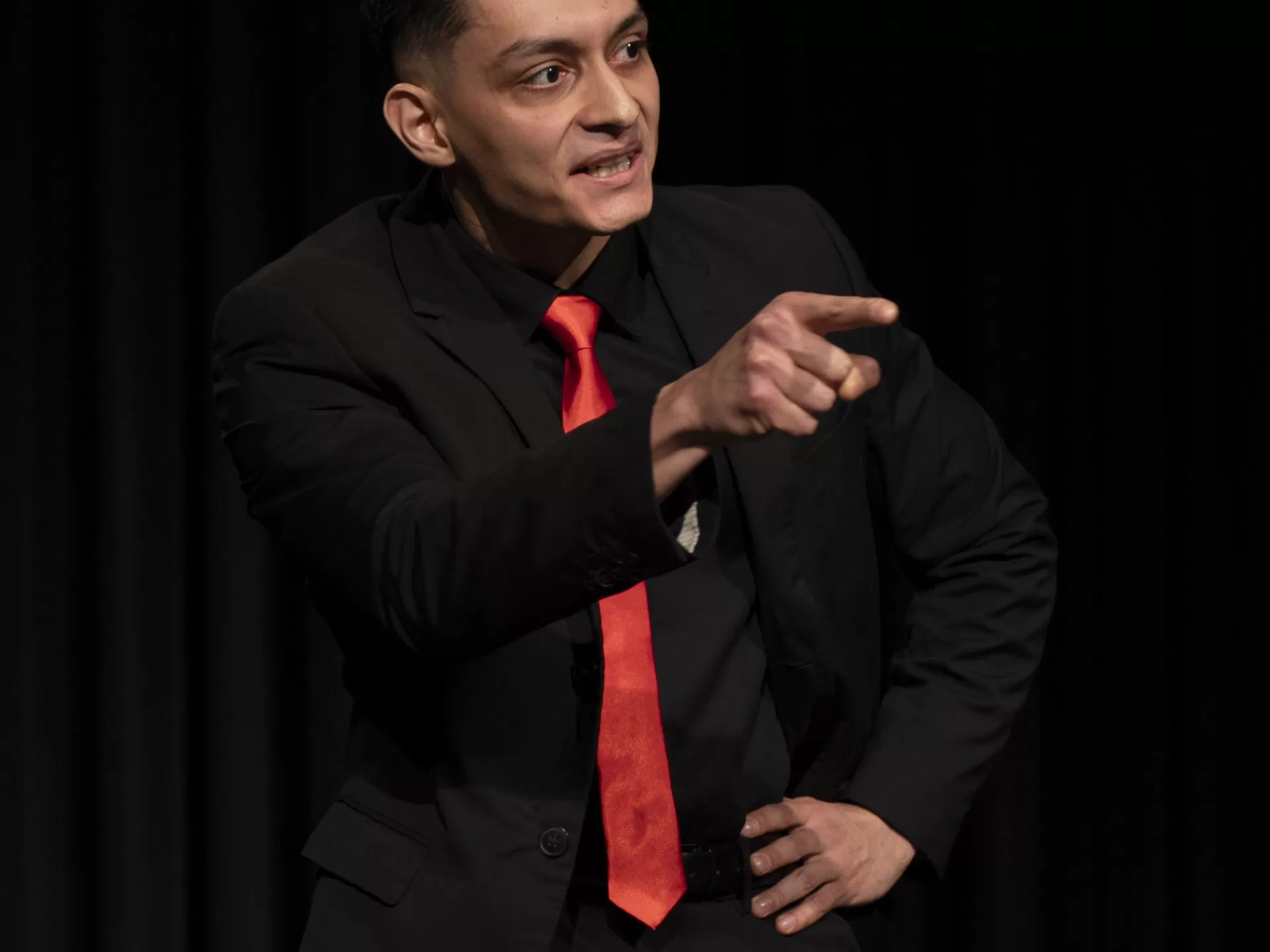 Ein Mann im schwarzen Anzug schaut wütend und zeigt mit einem Finger.