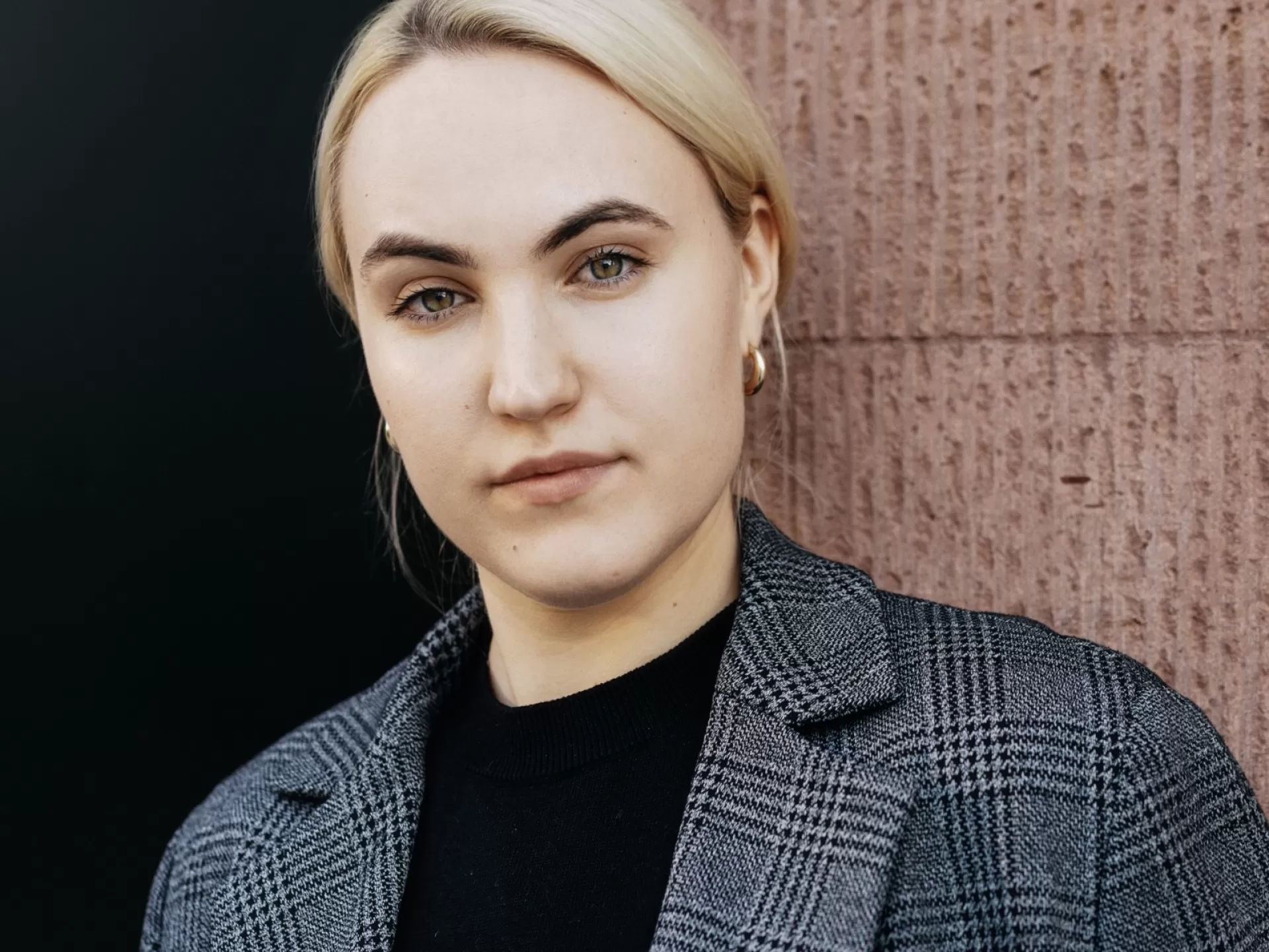Frau in einer grauen Jacke mit dem ernsten Blick und zurückgekämmten Haaren