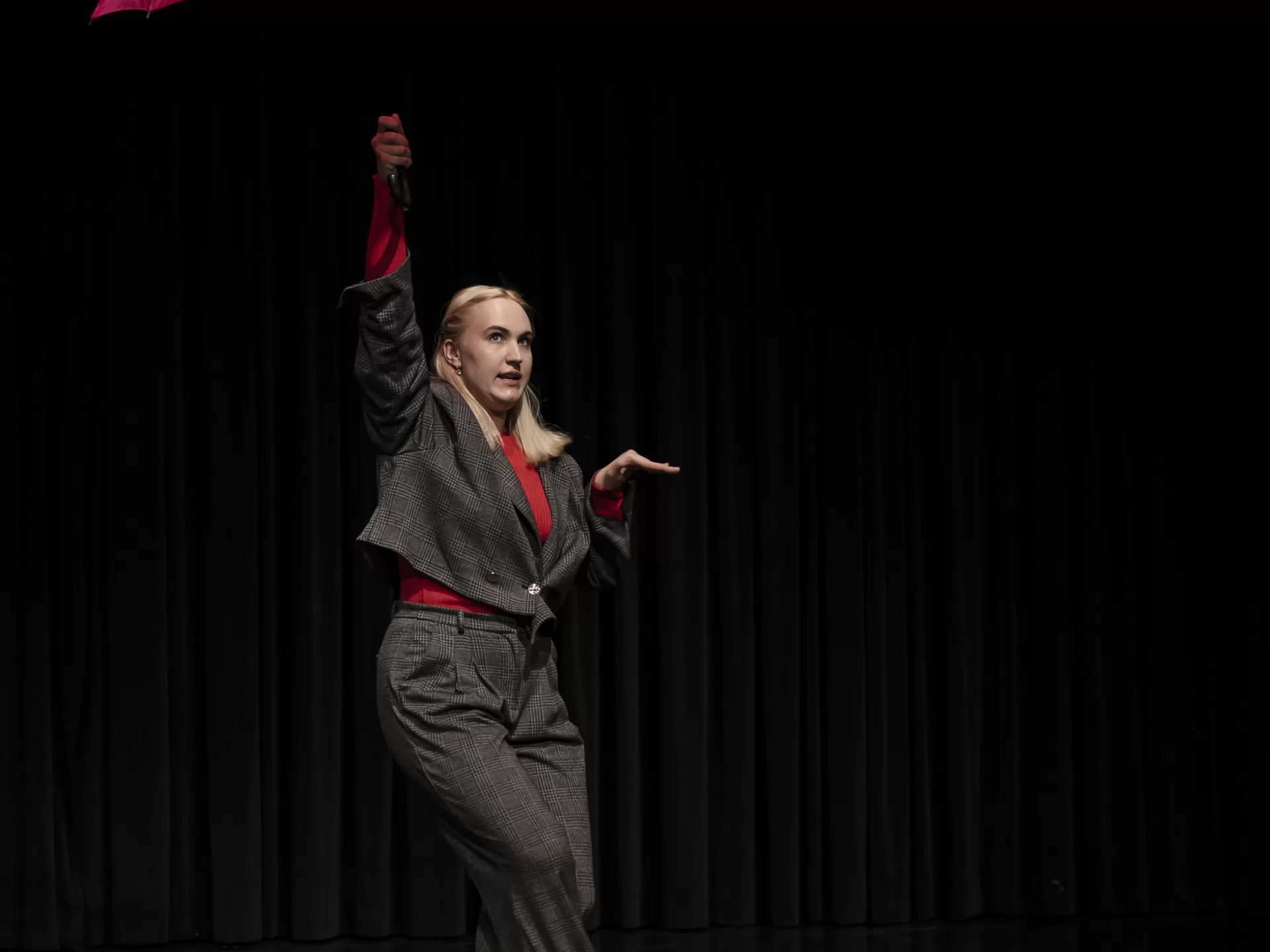 Eine Frau in einem grauen Anzug und einem rosa Regenschirm in der Hand