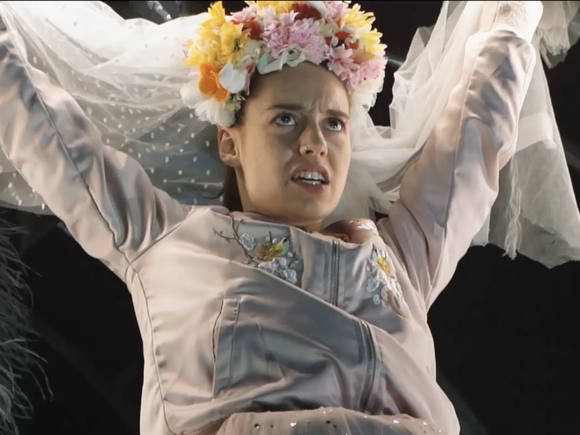 Frau mit Blumenkranz und Schleier auf dem Kopf.