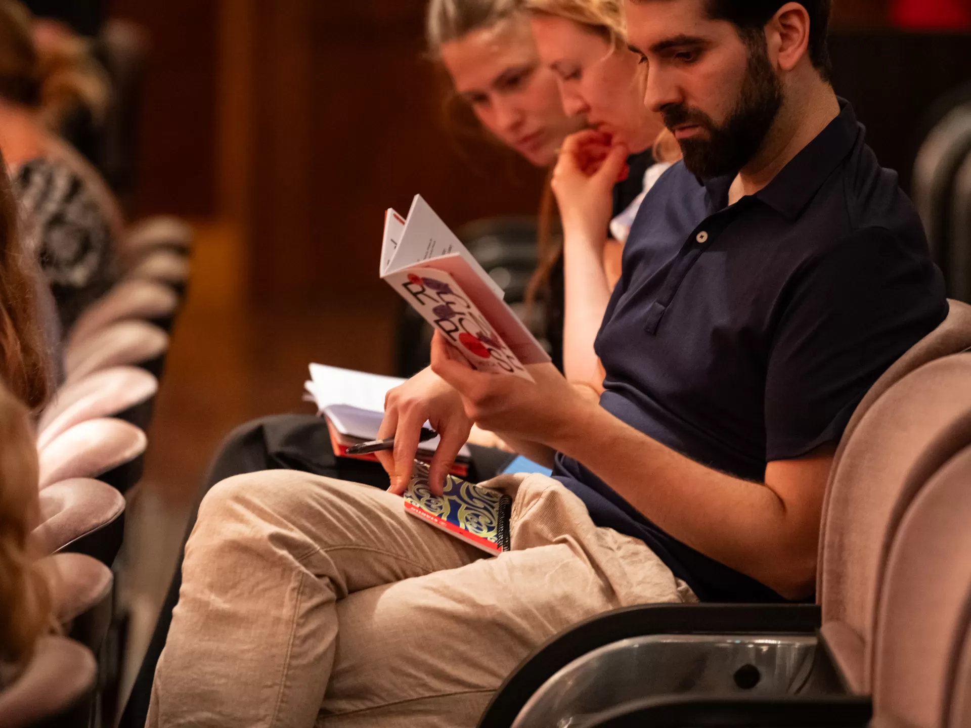 Ein Zuschauer sitzt auf seinem Platz und studiert das Response-Programmheft.