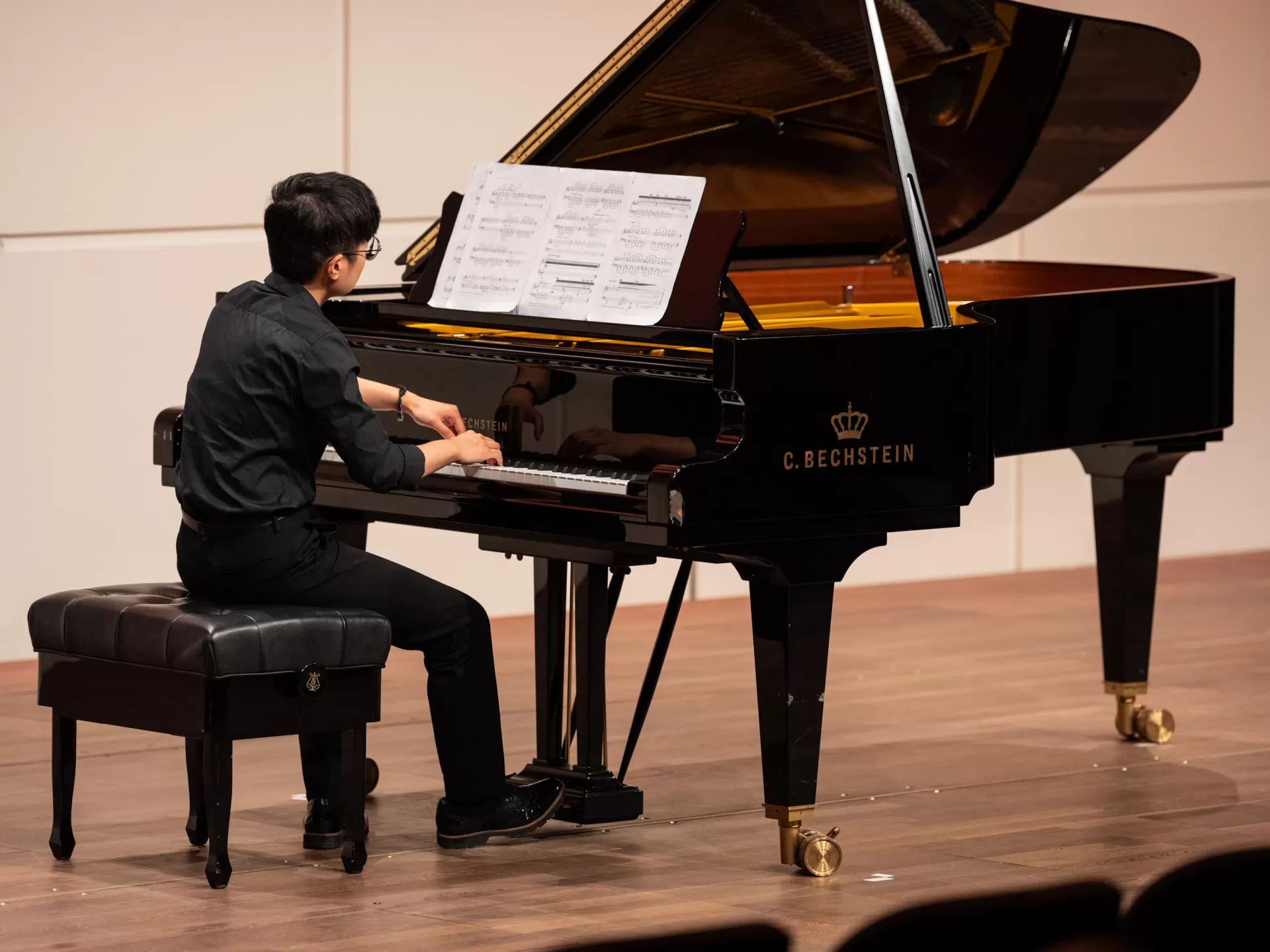 Ein schwarz gekleideter Mensch spielt an einem schwarzen Flügel.