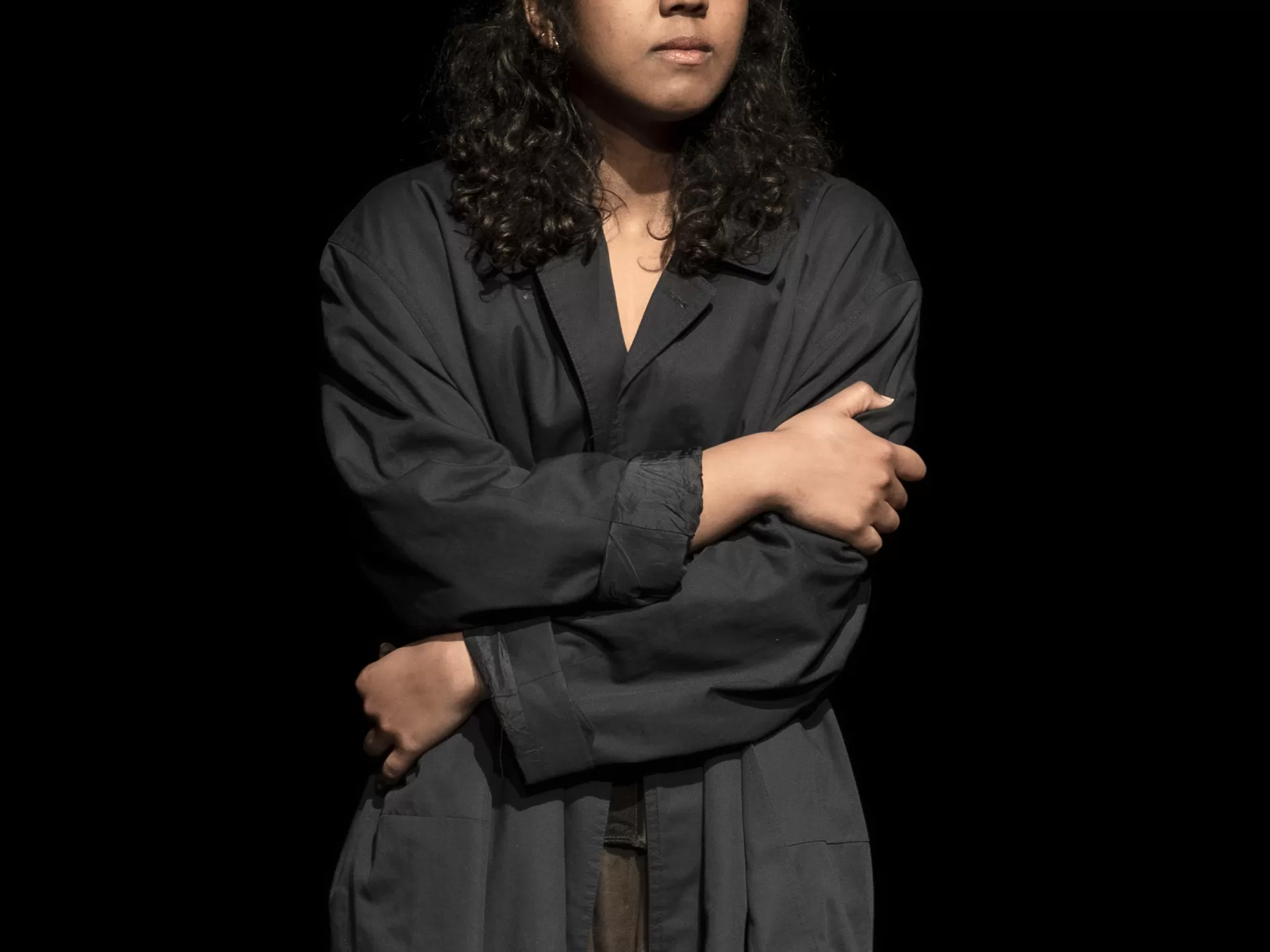 Frau in dunkler Kleidung steht mit verschränkten Armen.