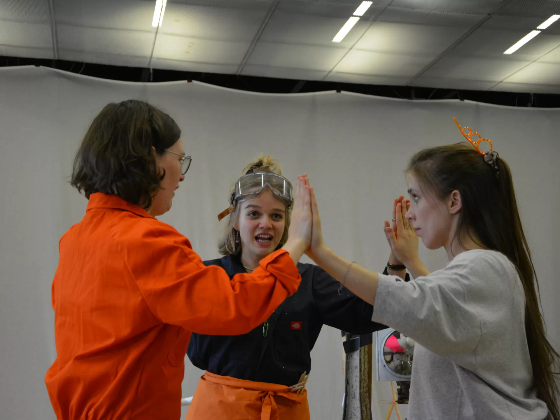 Probenfoto: Drei Darstellerinnen stehen im Kreis und drücken ihre Handflächen aneinander.