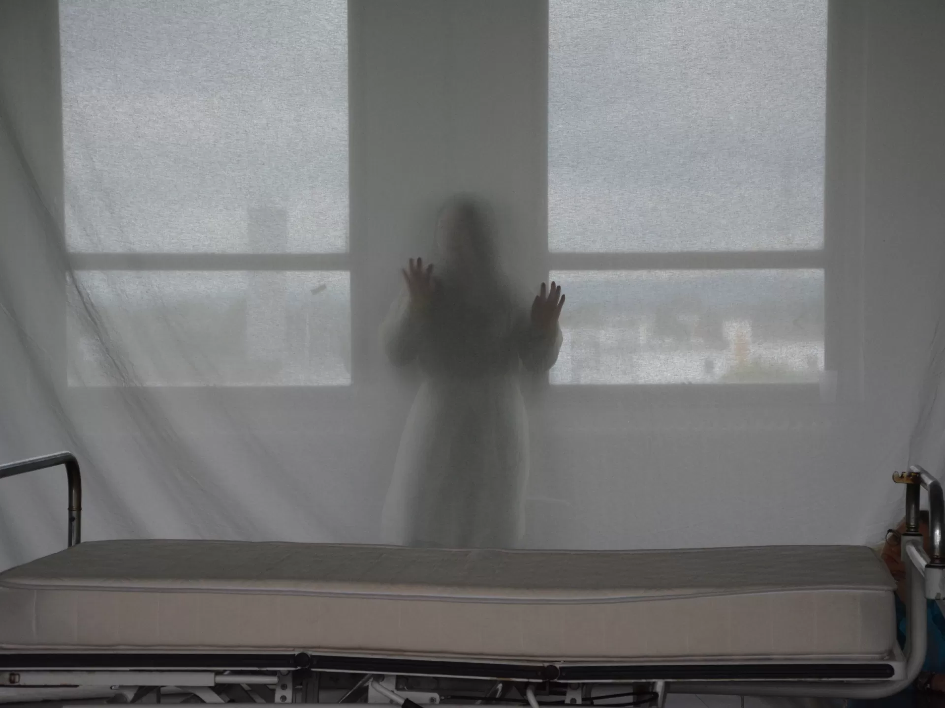 Eine Person steht hinter einer halbdurchsichtigen Leinwand.