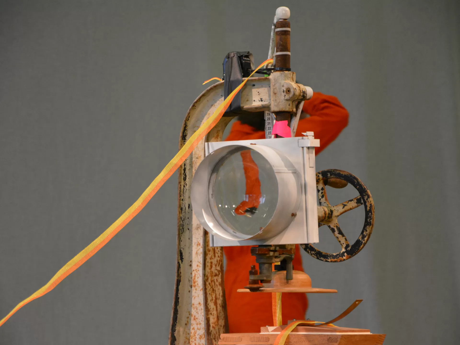 Ein Stück Bühnenbild der "Moira"-Inszenierung. Durch eine runde Linse sieht man die Darstellerin dahinter auf dem Kopf.