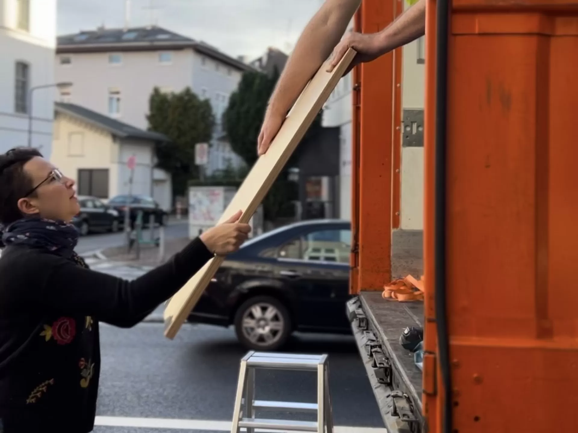 Ein Handwerker gibt einer Studentin eine Holzplatte aus dem LWK heraus an.