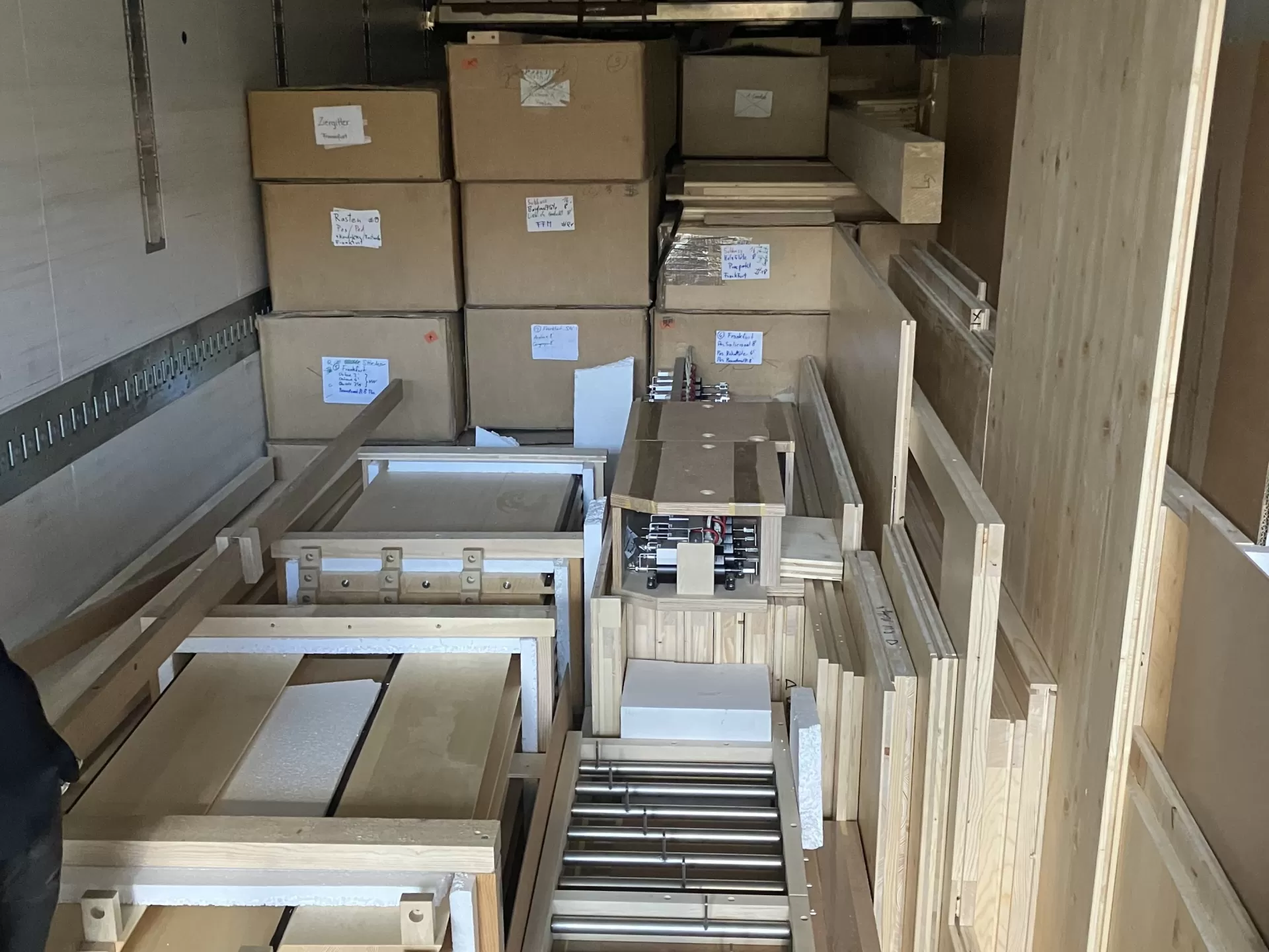 Der LKW ist fast voll geladen. Im Vordergrund liegen viele Holzplatten, im Hintergrund stapeln sich Kartons.