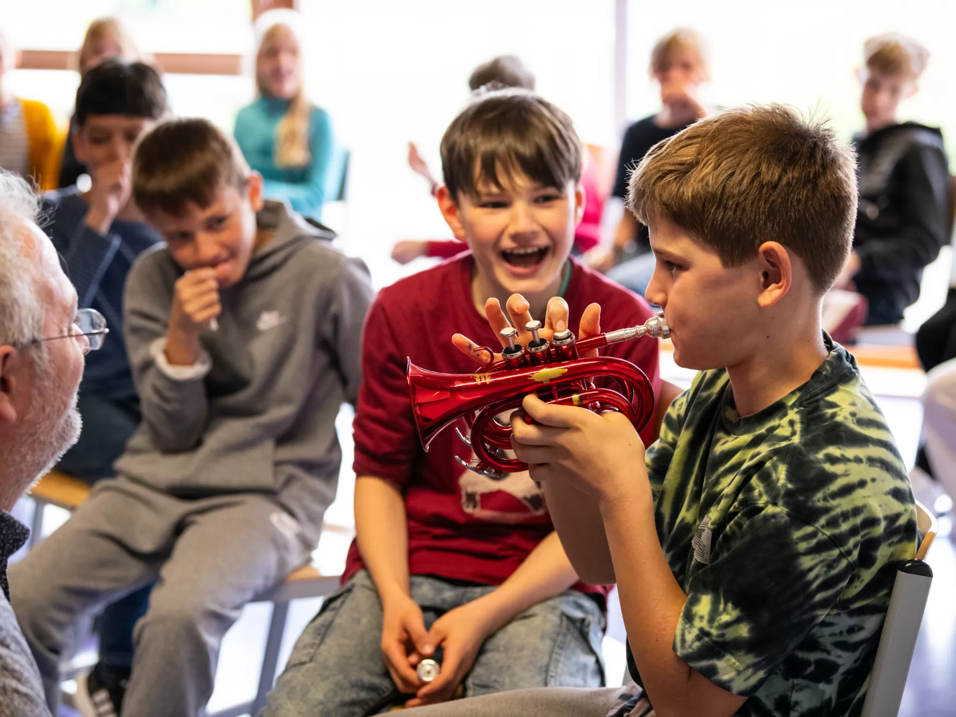 Ein Schüler probiert eine kleine rote Trompete aus.