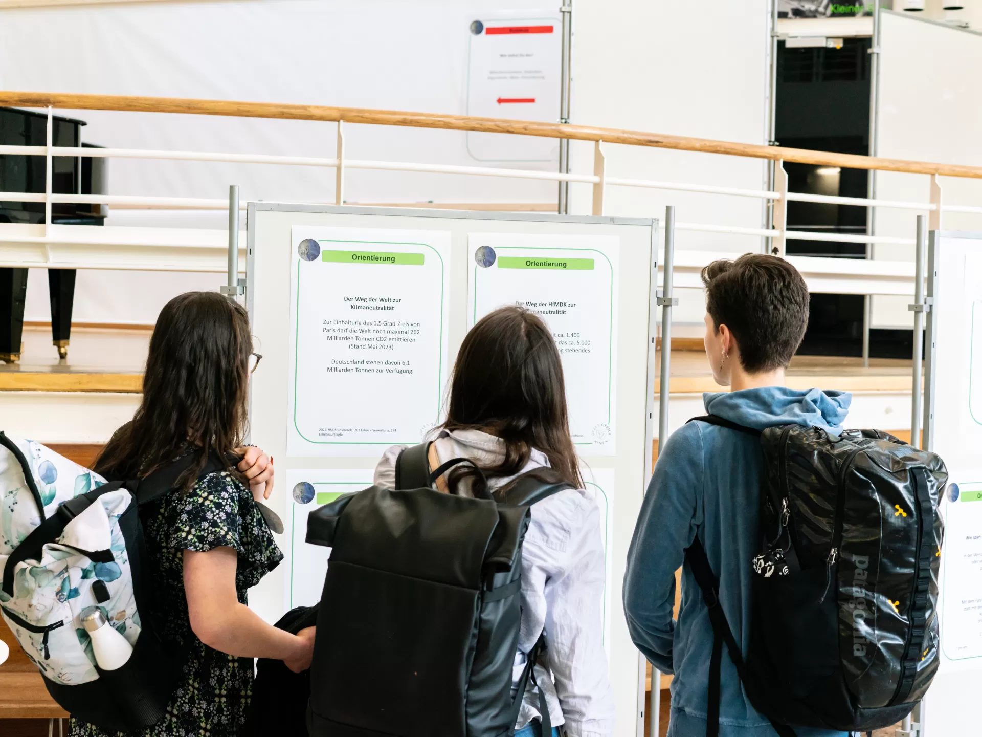 Studierende schauen sich Aufsteller im Foyer an, an denen Infos zum Thema Nachhaltigkeit hängen.