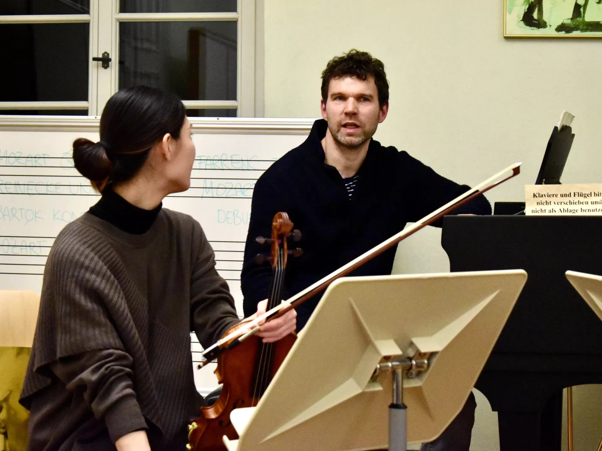 Ein Musiker und eine Musikerin mit ihren Instrumenten diskutieren.