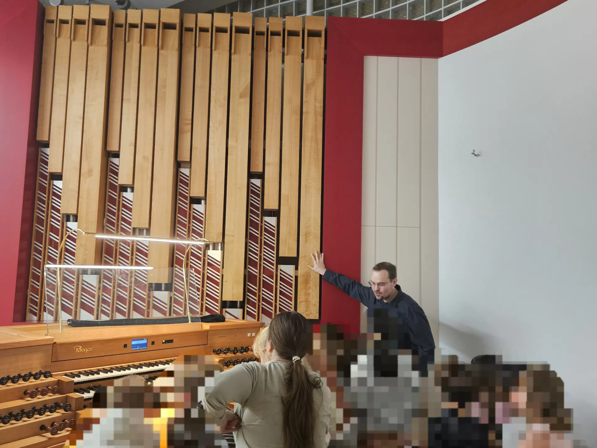 Lukas Euler steht an der Orgel und erklärt, zahlreiche Kinder stehen dicht gedrängt um den Spieltisch herum.