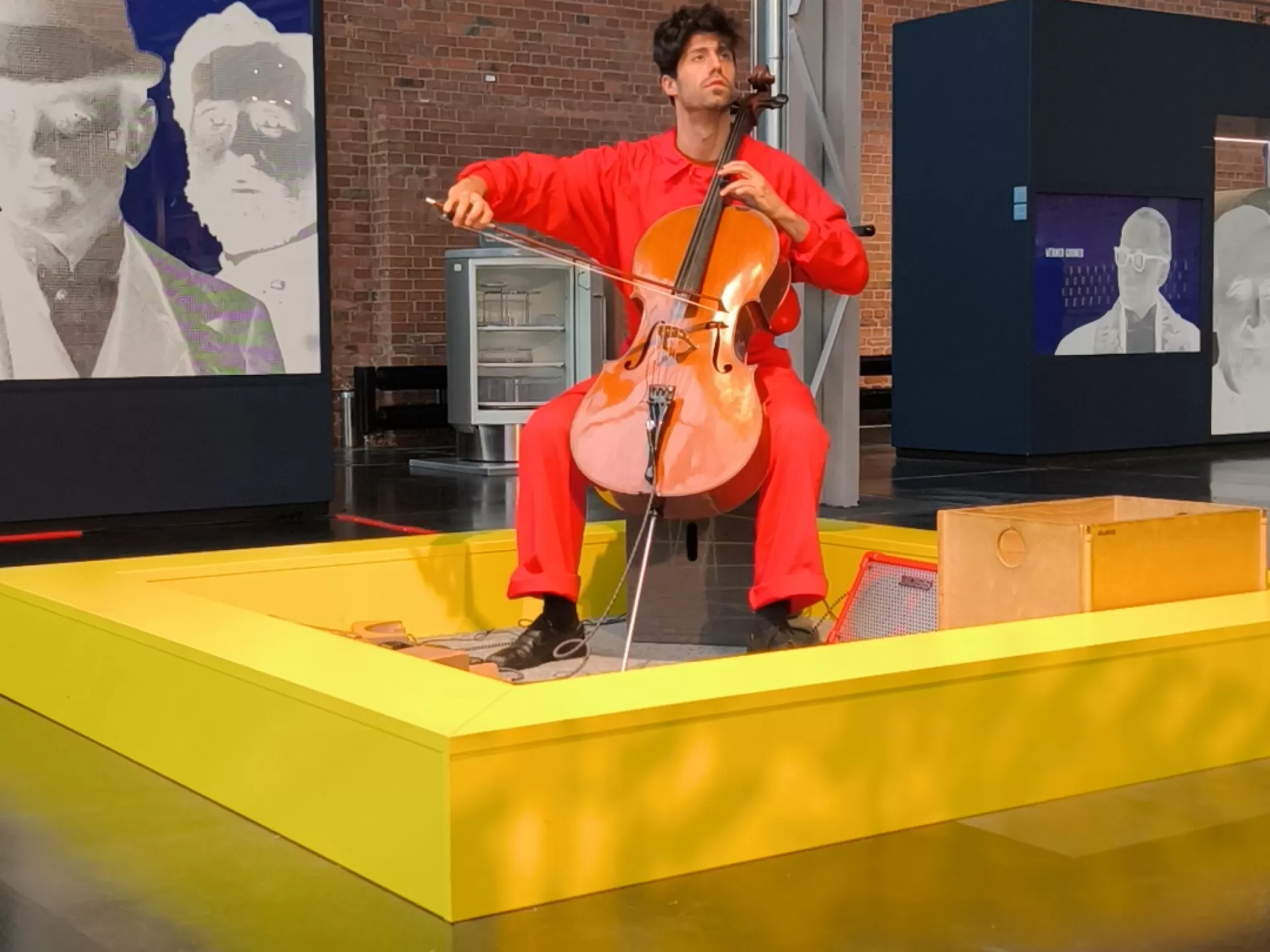 Ein Cellist in einem roten Overall musiziert im Industriemuseum