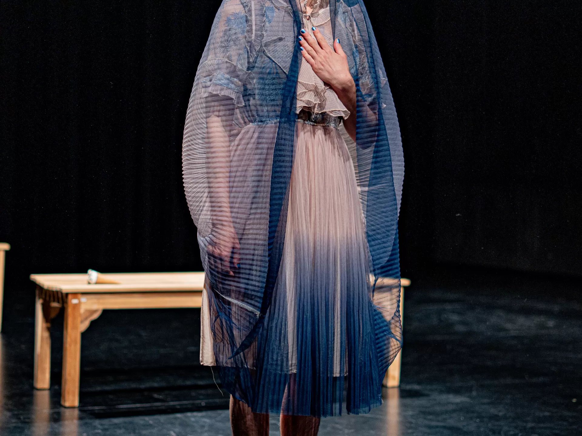 Lisa Freiberger hat den Rock ihres Kleides als Schleier über den Kopf gezogen und hält eine Hand an die Brust.