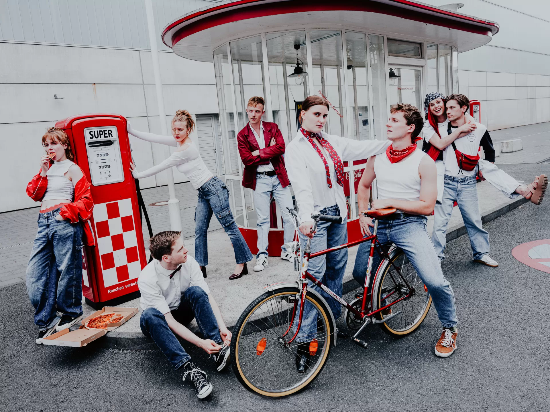 Gruppe von 8 Personen in weißer und roter Kleidung an einer Tankstelle.