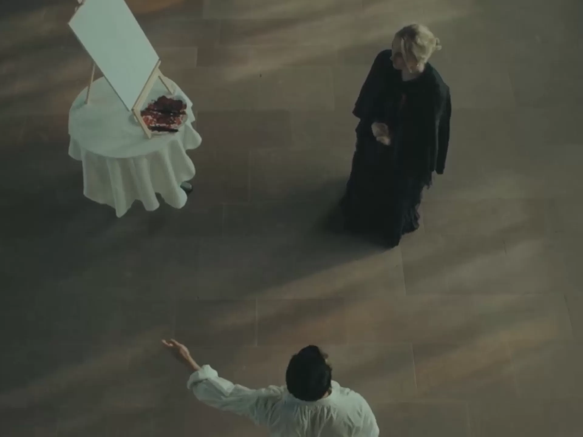 Aus der Vogelperspektive sieht man einen Mann und eine Frau vor einer Kunstleinwand.