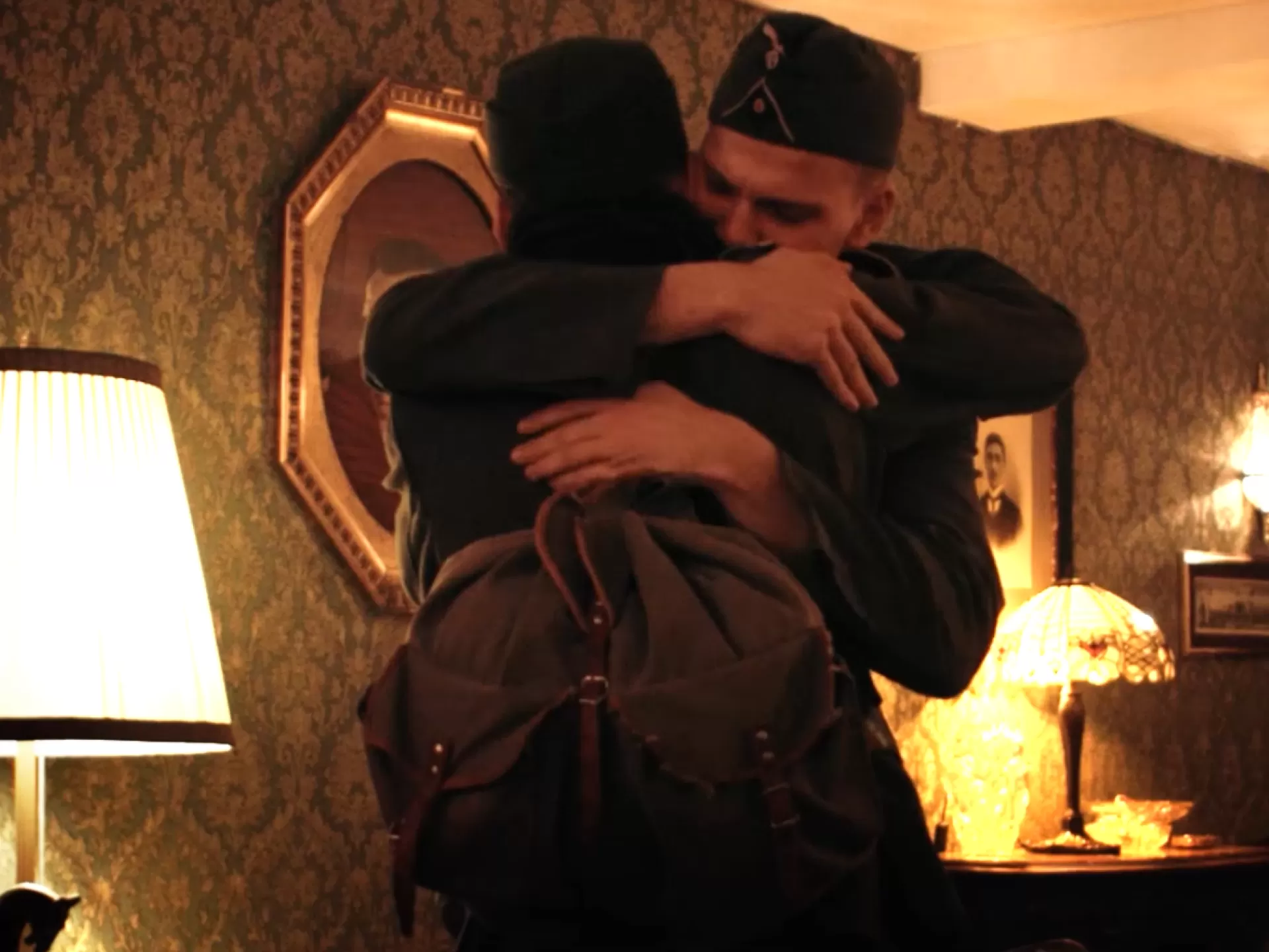 Zwei Männer in Wehrmachtsuniformen umarmen sich.